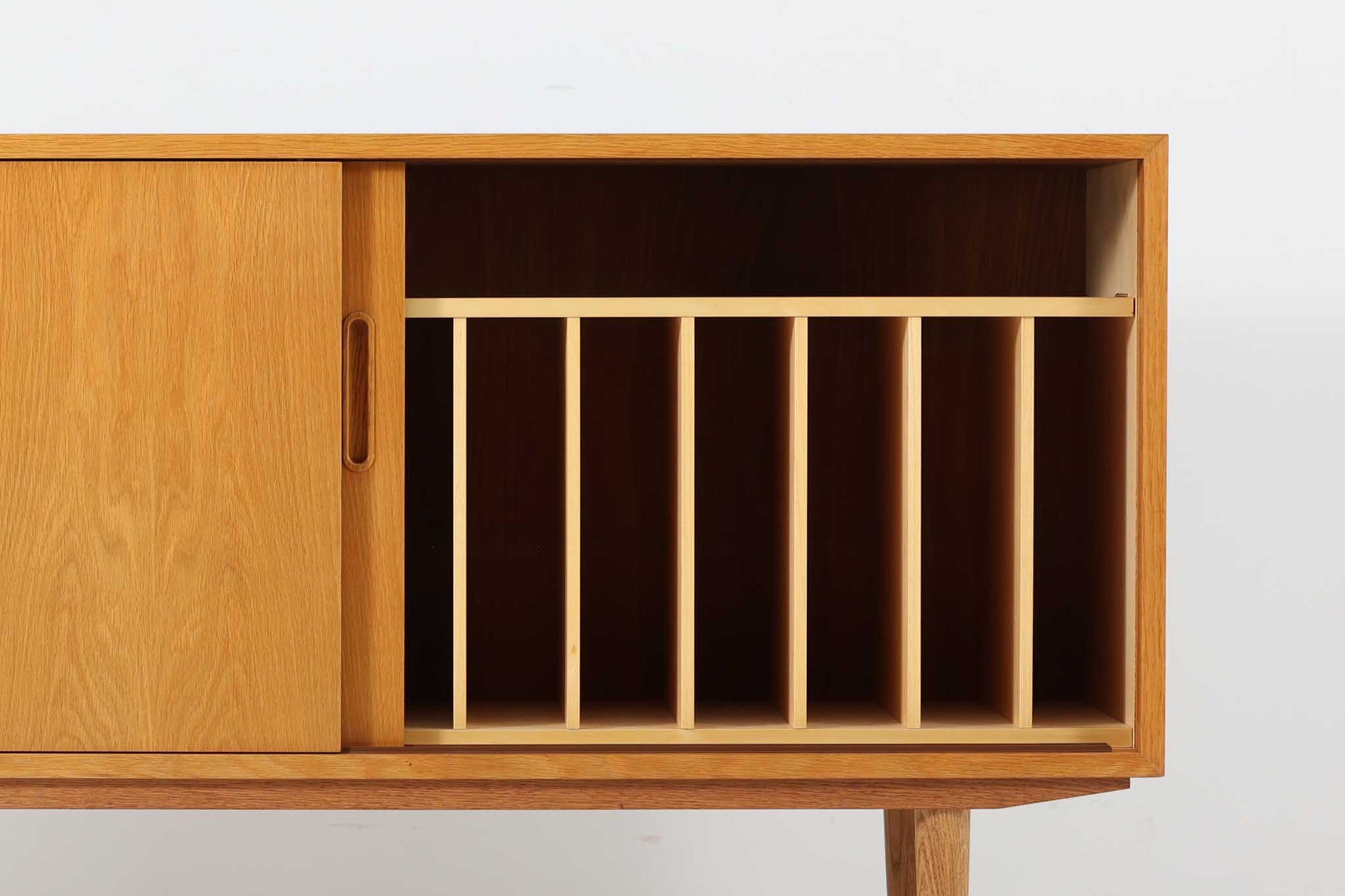 北欧より買い付けたサイドボードです。収納部の右側には、元々レコード収納用として設計されていたと思われる取り外し可能な縦仕切りがあり、幅の調整も可能です。棚板は取り外しできませんが、縦仕切りは全て取り外し可能で、大きなアイテムの収納にも対応できます。左側の収納部には、取り外しや可動が可能な引き出しが2杯備わっており、使い勝手も良好です。シンプルながらも高いクオリティを誇り、デンマークの家具デザイナーPoul Hundevadによってデザインされた本作は、デンマークの厳しい品質基準を満たした「DANISH FURNITUREmAKE'S CONTROL」のロゴシールが付いております。