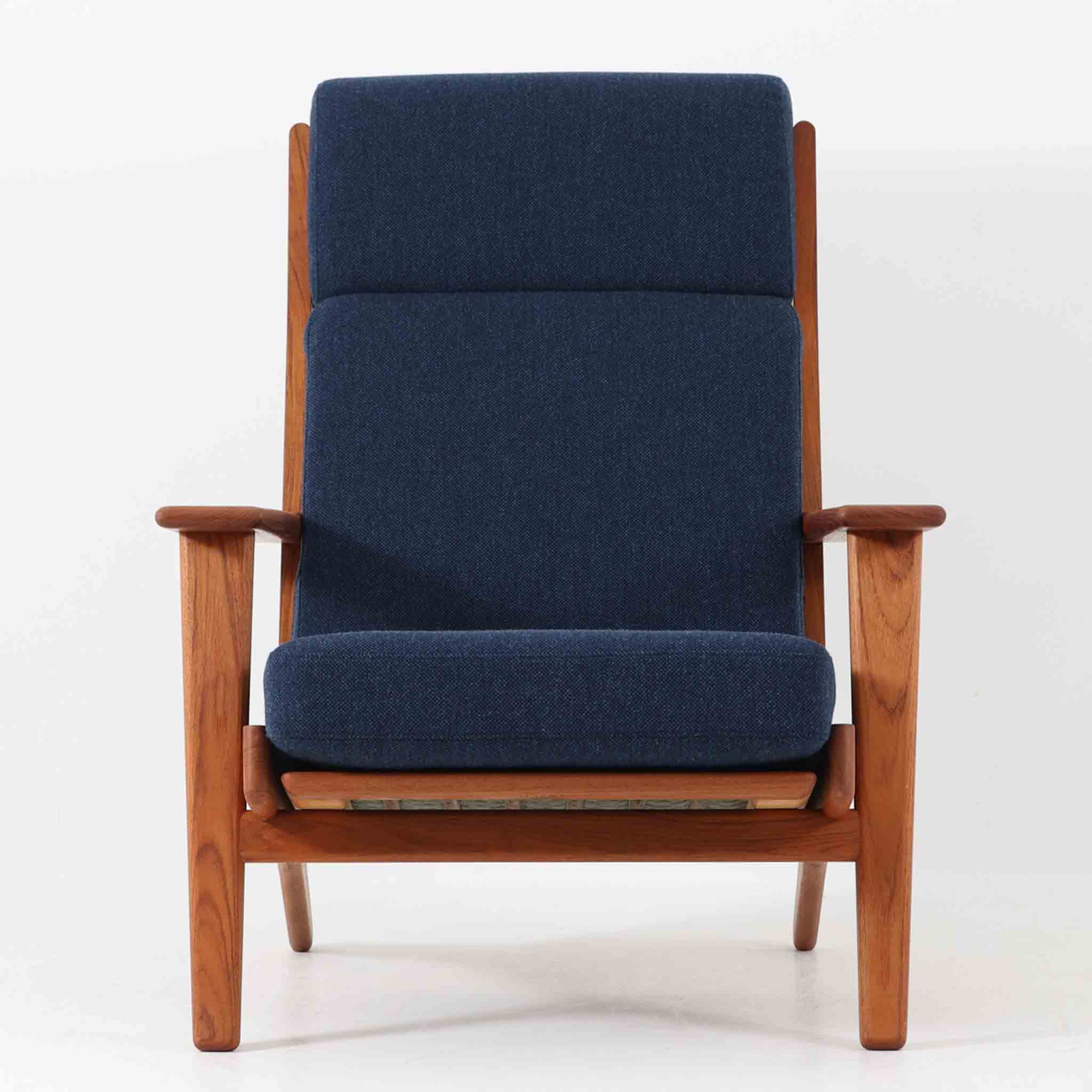 Hans J. Wegnerがデザインし、Getama社によって製造されたGe290Aは、現在では希少となったチーク材のフレームに深いブルーの張地が美しく調和した、ハイバック仕様のビンテージシングルソファです。緩やかに傾斜する背もたれと幅広のアームが身体を包み込むような快適な座り心地を実現し、日常に上質な寛ぎをもたらします。背面の格子状フレームや真鍮ビスなど、細部にまでウェグナーの美意識が宿り、北欧家具の名作としてリビングの主役にふさわしい存在感を放ちます。座面クッションにはスプリングが内包されていますが、背もたれにはウレタンのみが使用されています。