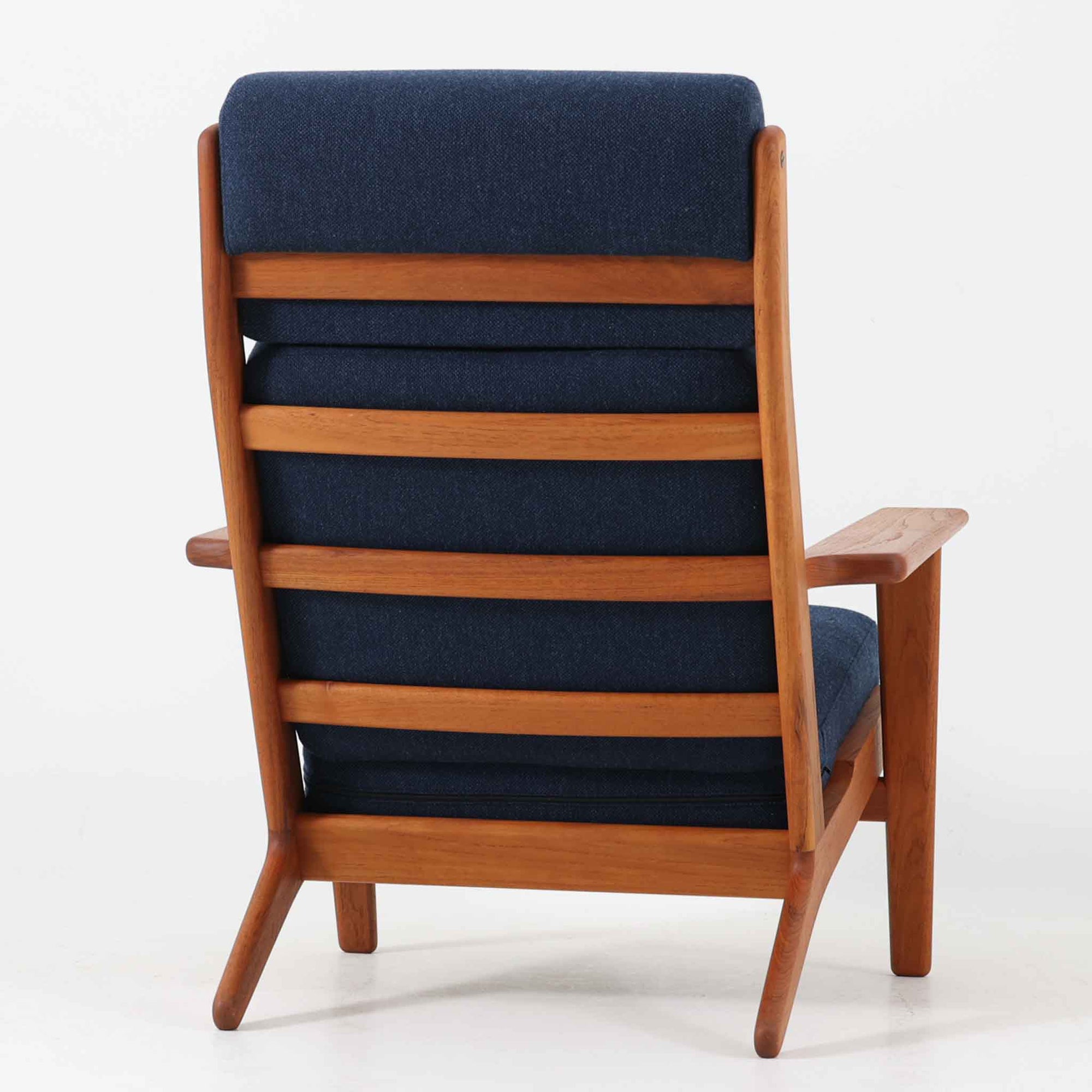 Hans J. Wegnerがデザインし、Getama社によって製造されたGe290Aは、現在では希少となったチーク材のフレームに深いブルーの張地が美しく調和した、ハイバック仕様のビンテージシングルソファです。緩やかに傾斜する背もたれと幅広のアームが身体を包み込むような快適な座り心地を実現し、日常に上質な寛ぎをもたらします。背面の格子状フレームや真鍮ビスなど、細部にまでウェグナーの美意識が宿り、北欧家具の名作としてリビングの主役にふさわしい存在感を放ちます。座面クッションにはスプリングが内包されていますが、背もたれにはウレタンのみが使用されています。