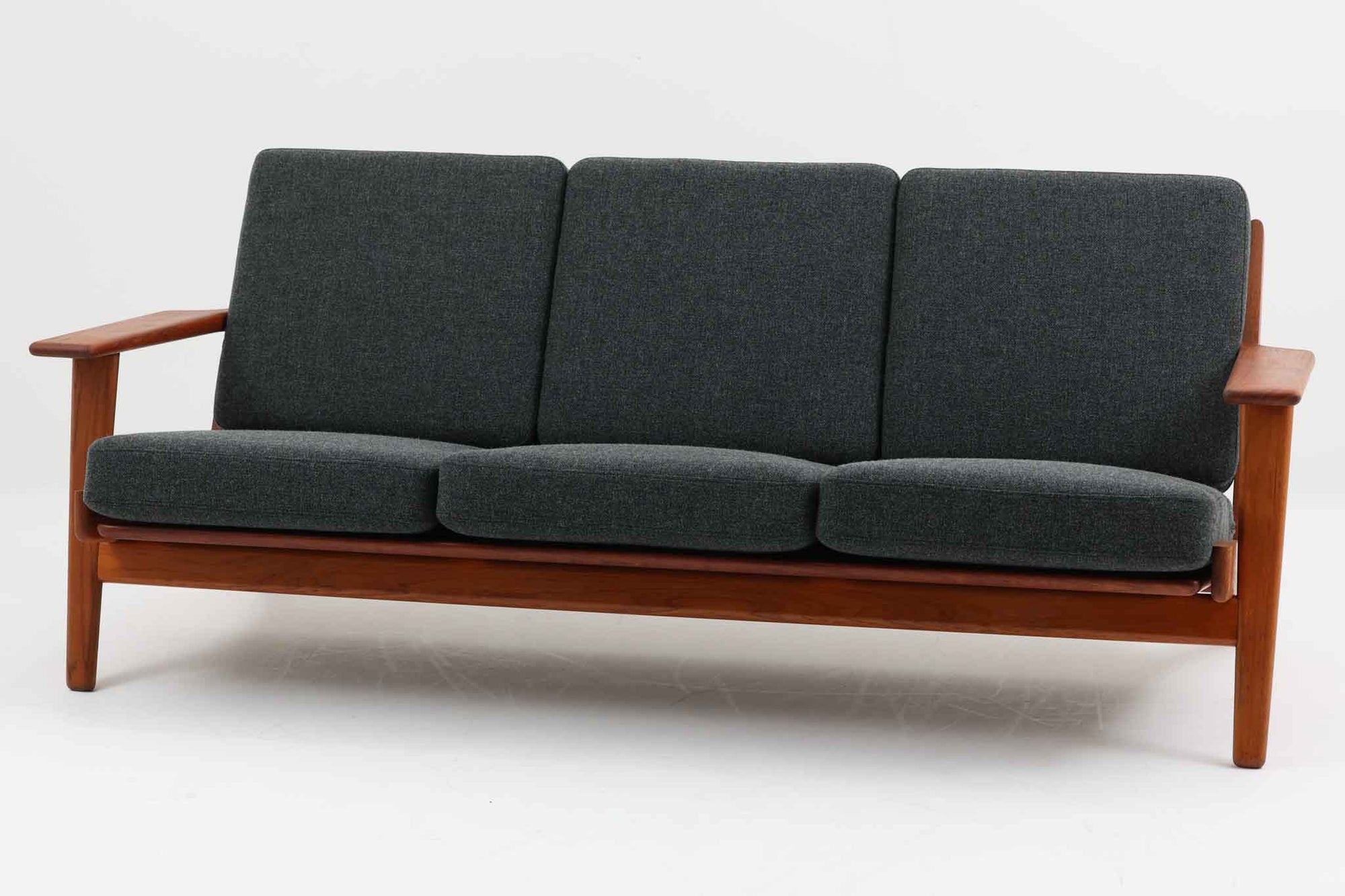 北欧家具を代表するソファ『GE290』です。現在リプロダクト品が販売されていますが、こちらは本物です。元々はベッド会社であるGETAmA社ならではのコイルスプリングが内包されたクッションの座り心地は、弾力があり心地良く、読書や映画などのリラックスタイムに最適です。立ち上がる際も適度なはね返りがあるので、動く時に億劫になる事はありません。Hans J. Wegnerならではの時代を超えた美しいデザインも魅力のひとつ。横や背面から眺めると、また異なる表情が楽しめます。さらに、こちらは現行品では手に入らない希少なチーク材モデル。素材の質感と温かみを存分に味わえる逸品です。