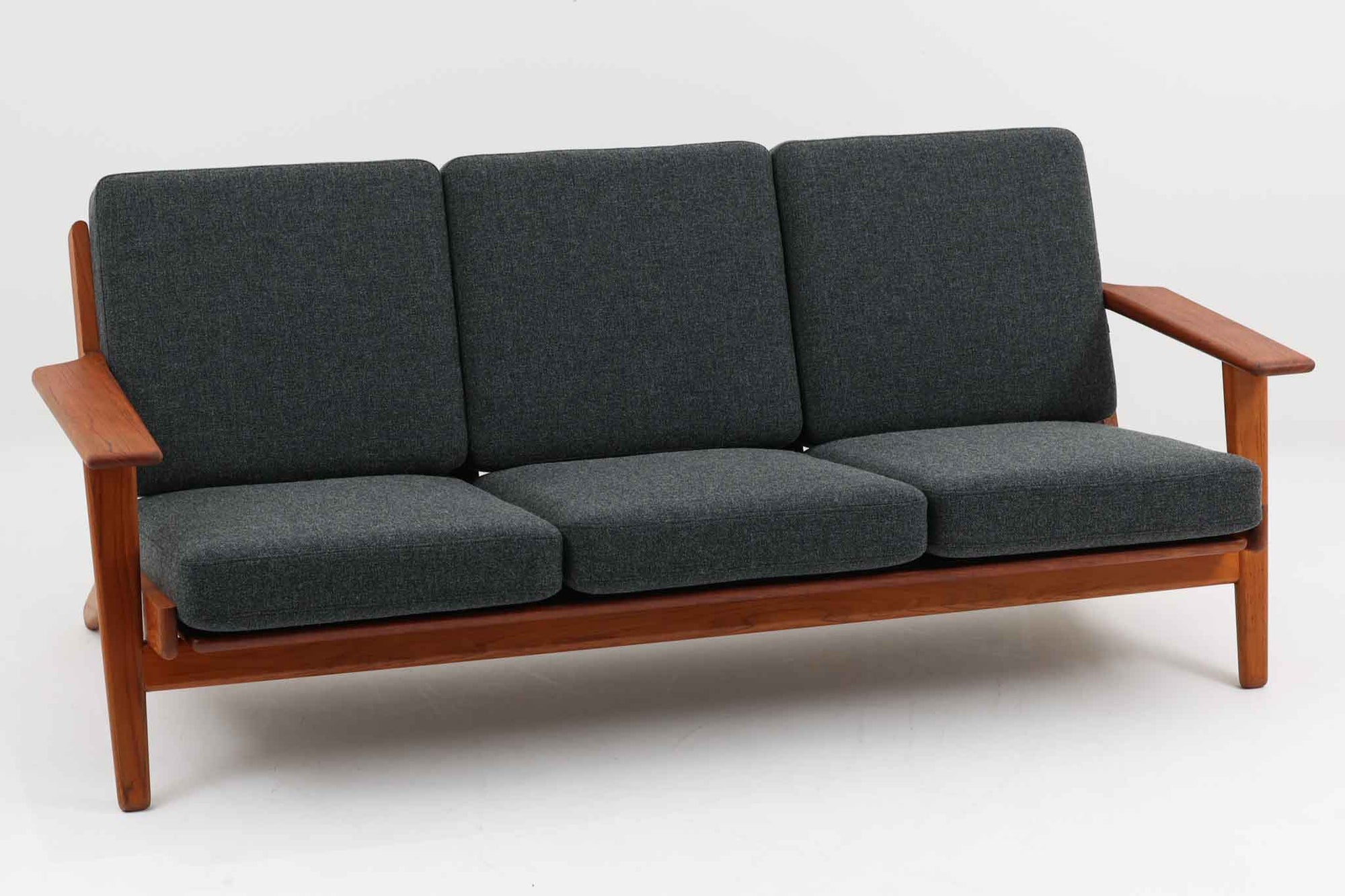 北欧家具を代表するソファ『GE290』です。現在リプロダクト品が販売されていますが、こちらは本物です。元々はベッド会社であるGETAmA社ならではのコイルスプリングが内包されたクッションの座り心地は、弾力があり心地良く、読書や映画などのリラックスタイムに最適です。立ち上がる際も適度なはね返りがあるので、動く時に億劫になる事はありません。Hans J. Wegnerならではの時代を超えた美しいデザインも魅力のひとつ。横や背面から眺めると、また異なる表情が楽しめます。さらに、こちらは現行品では手に入らない希少なチーク材モデル。素材の質感と温かみを存分に味わえる逸品です。