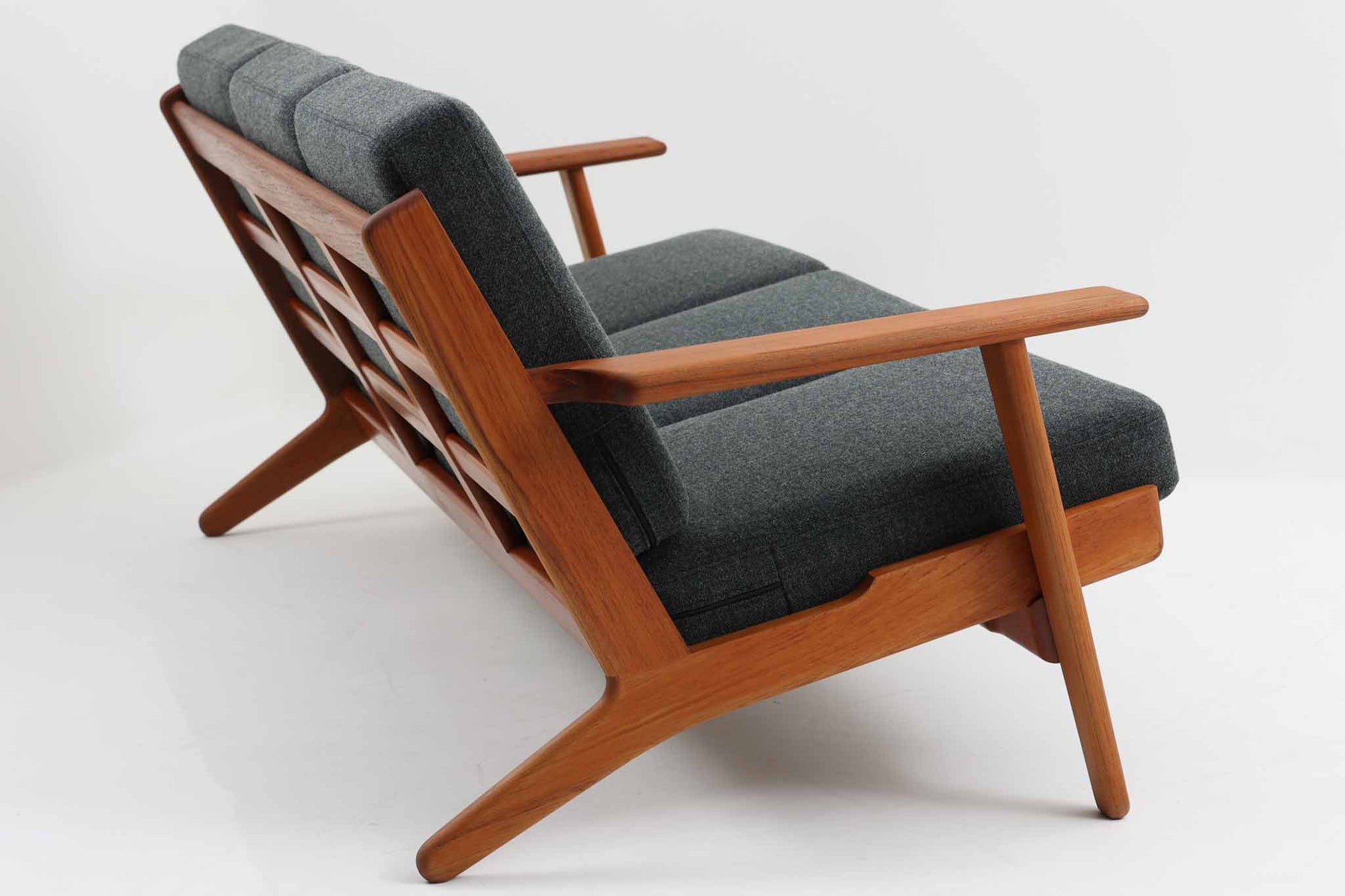 北欧家具を代表するソファ『GE290』です。現在リプロダクト品が販売されていますが、こちらは本物です。元々はベッド会社であるGETAmA社ならではのコイルスプリングが内包されたクッションの座り心地は、弾力があり心地良く、読書や映画などのリラックスタイムに最適です。立ち上がる際も適度なはね返りがあるので、動く時に億劫になる事はありません。Hans J. Wegnerならではの時代を超えた美しいデザインも魅力のひとつ。横や背面から眺めると、また異なる表情が楽しめます。さらに、こちらは現行品では手に入らない希少なチーク材モデル。素材の質感と温かみを存分に味わえる逸品です。