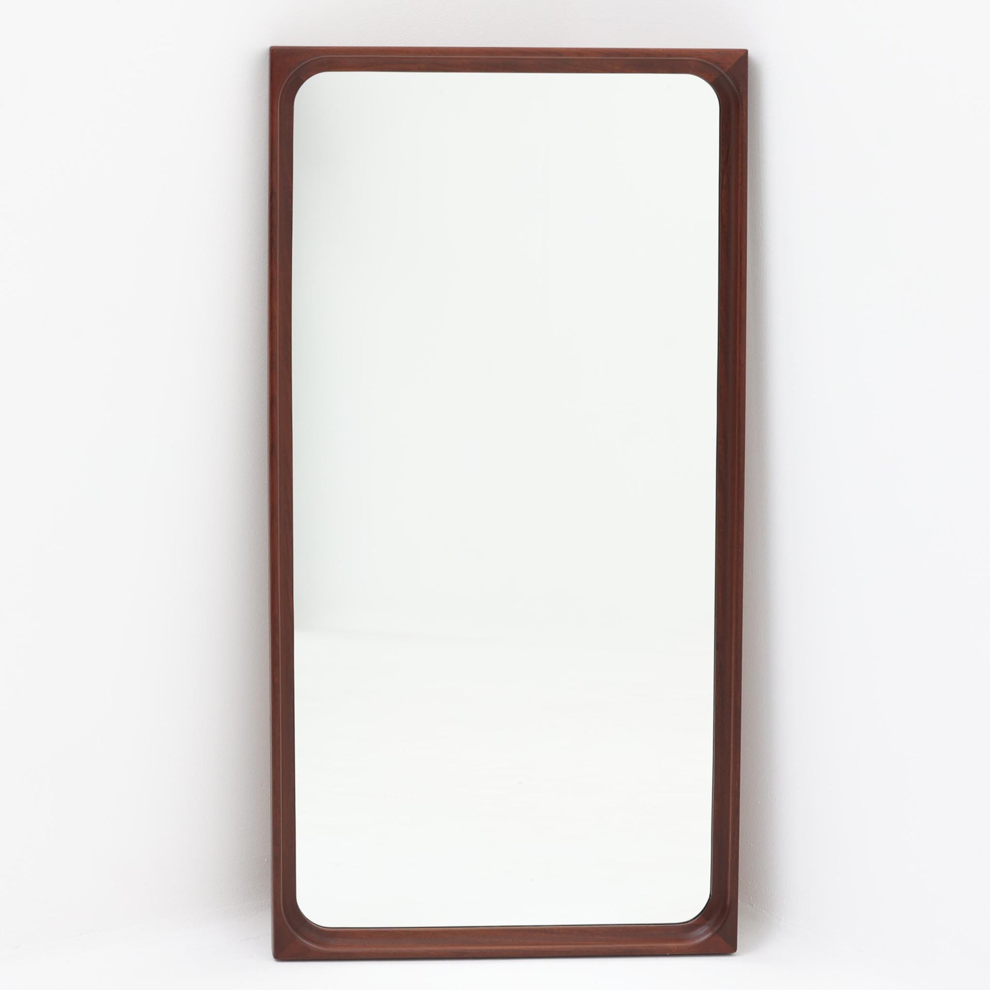 Egon Bro Petersenによるデザインの立て掛けミラーは、希少なアフロモシア材を贅沢に用いた北欧ビンテージ品で、フレーム内側の緩やかな曲線加工に、北欧らしい洗練された木工技術が感じられます。高さ87cmの程よいサイズで、玄関や寝室にさりげなく寄り添いながら、空間に深みと落ち着きを添えてくれます。背面にはモデルナンバーの刻印も確認でき、素材美と機能美が調和した一品です。