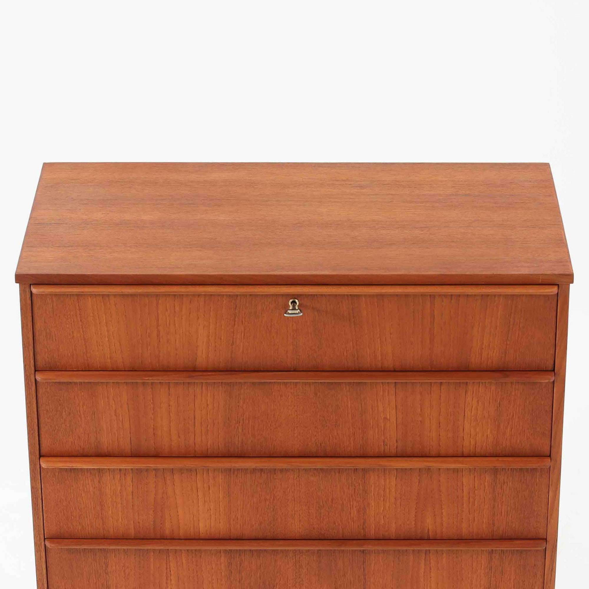 チーク材の美しい木目が前面に現れた、デンマークで作られた4段チェストです。直線を基調とした端正な佇まいと、引き出し上部に取手を設けたミニマルな構造が北欧らしい洗練を感じさせます。脚部は細身で床からの抜け感があり、空間を軽やかに演出します。収納力の高い4段構成で、衣類や書類、小物整理まで幅広く対応し、リビングや寝室、書斎など多様なシーンで活躍します。経年により深みを増したチークの色合いと質感は、ビンテージ家具ならではの魅力です。