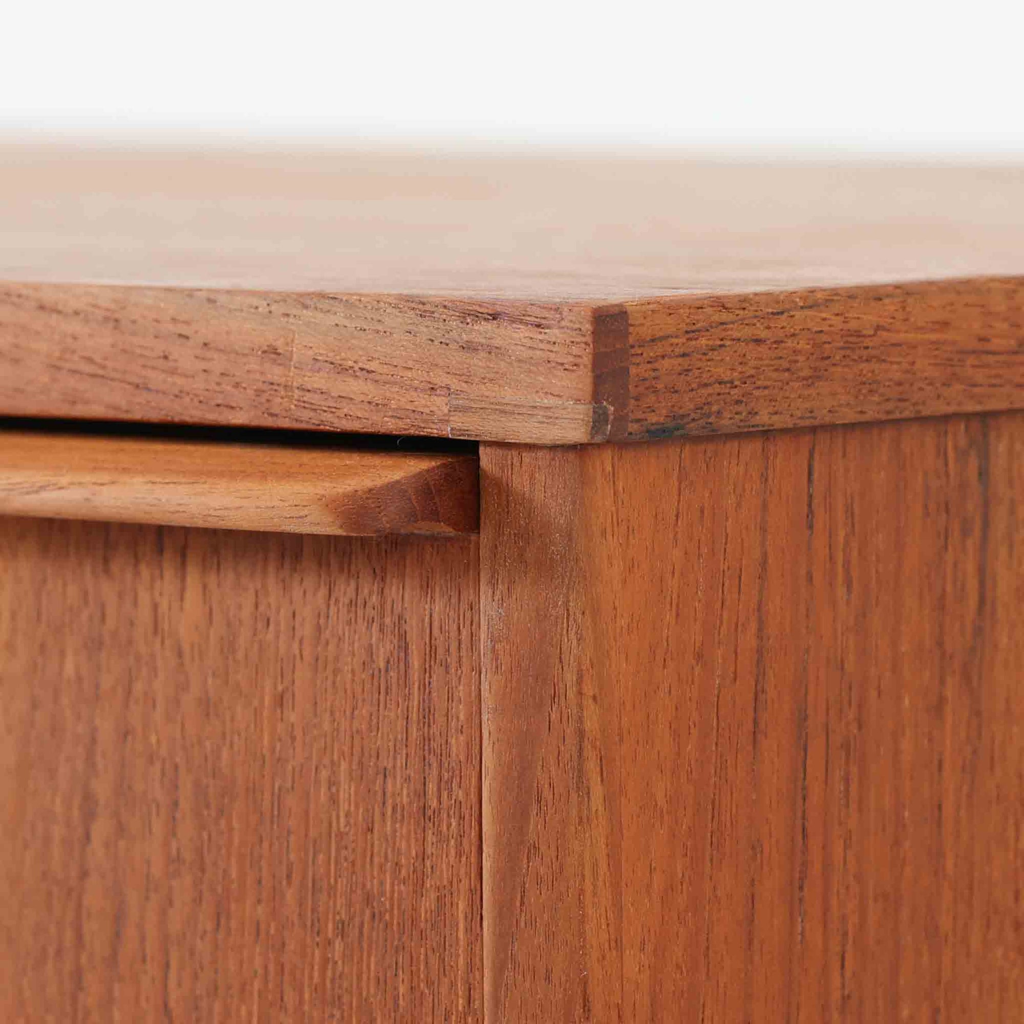 チーク材の美しい木目が前面に現れた、デンマークで作られた4段チェストです。直線を基調とした端正な佇まいと、引き出し上部に取手を設けたミニマルな構造が北欧らしい洗練を感じさせます。脚部は細身で床からの抜け感があり、空間を軽やかに演出します。収納力の高い4段構成で、衣類や書類、小物整理まで幅広く対応し、リビングや寝室、書斎など多様なシーンで活躍します。経年により深みを増したチークの色合いと質感は、ビンテージ家具ならではの魅力です。