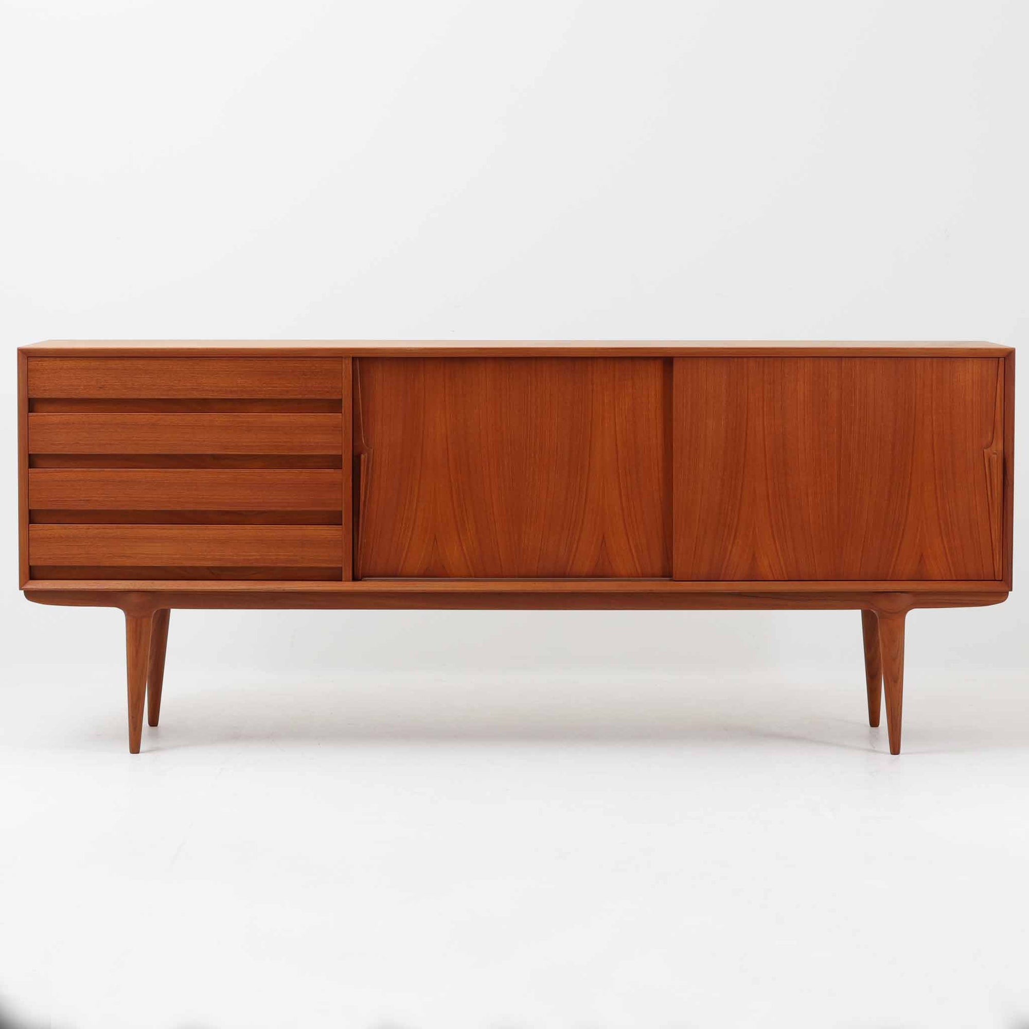 Gunni Omannがデザインし、Omann Jun社によって製造されたModel 18は、洗練されたラインと実用性を兼ね備えた北欧ビンテージの名作サイドボードです。チーク材の美しい木目が前面に広がり、引き出しとスライド扉の組み合わせが高い収納力を実現しています。特に繊細に削り出された取手や先細りの脚部が、軽やかで彫刻的な印象を与え、空間を上質に演出します。幅200cmのサイズ感は、リビングやダイニングの主役として活躍する存在感ある一台です。