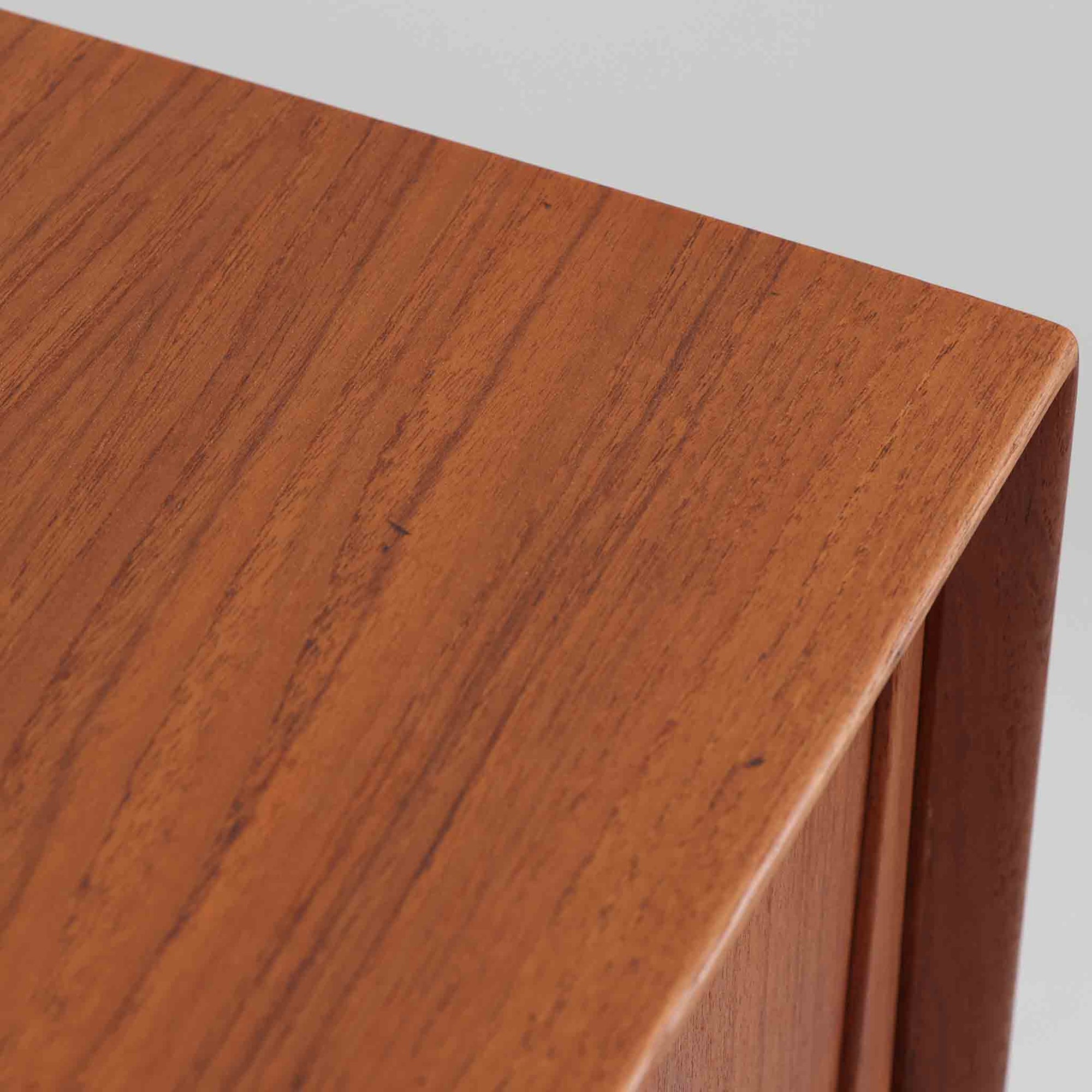 Gunni Omannがデザインし、Omann Jun社によって製造されたModel 18は、洗練されたラインと実用性を兼ね備えた北欧ビンテージの名作サイドボードです。チーク材の美しい木目が前面に広がり、引き出しとスライド扉の組み合わせが高い収納力を実現しています。特に繊細に削り出された取手や先細りの脚部が、軽やかで彫刻的な印象を与え、空間を上質に演出します。幅200cmのサイズ感は、リビングやダイニングの主役として活躍する存在感ある一台です。