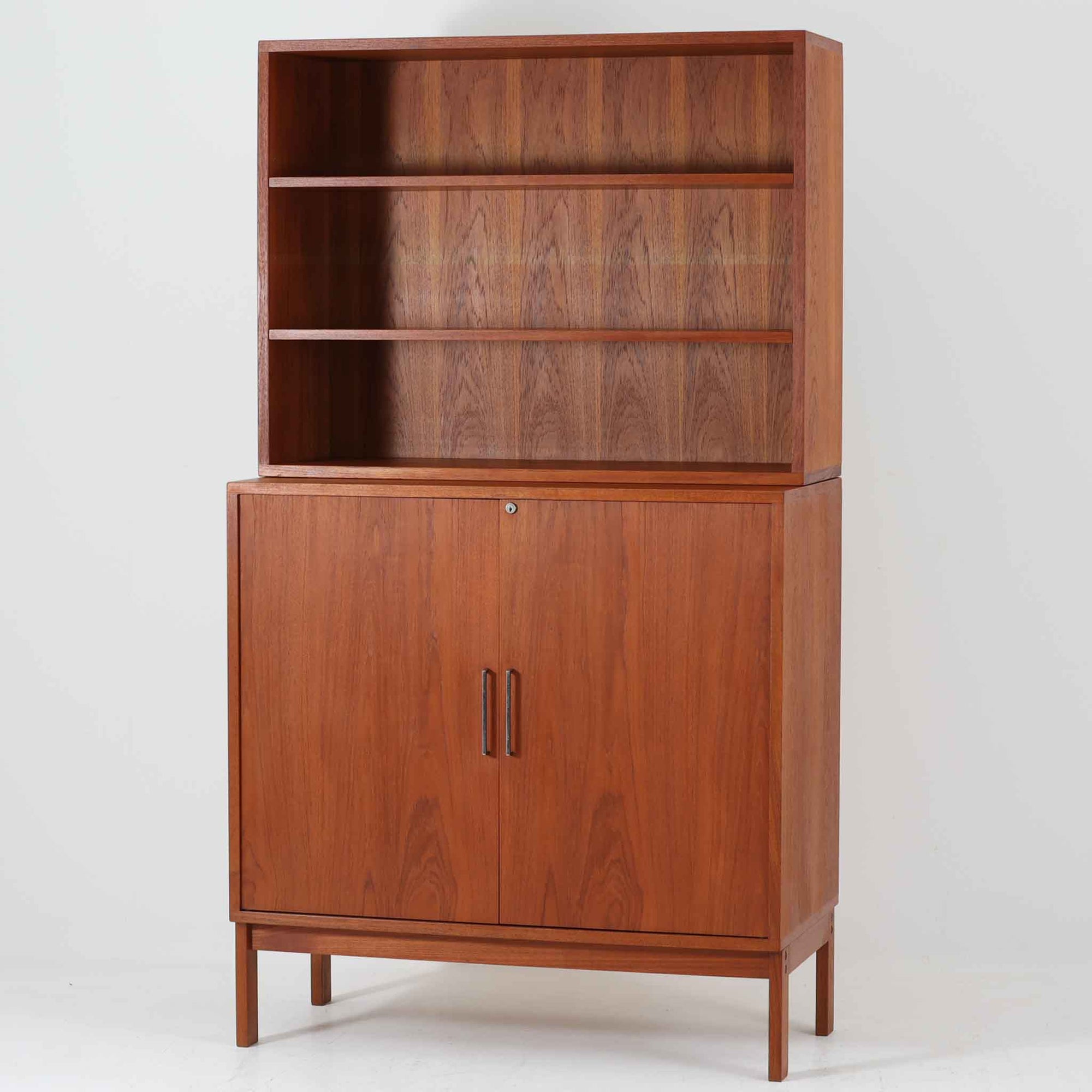 Bjerringbro Savvaerkによるチーク材キャビネットは、上下に分かれた構成と可動棚を備えた収納力の高さが魅力です。上段は3段のシェルフ、下段は珍しいポケットドア構造の扉内にA4サイズの書類が収納可能な引き出し型トレイが8段並び、書類や小物の整理に適しています。直線的で端正なフォルムと、チーク材の木目が美しく調和した佇まいは、北欧ビンテージらしい実用性と美しさを兼ね備えた逸品です。