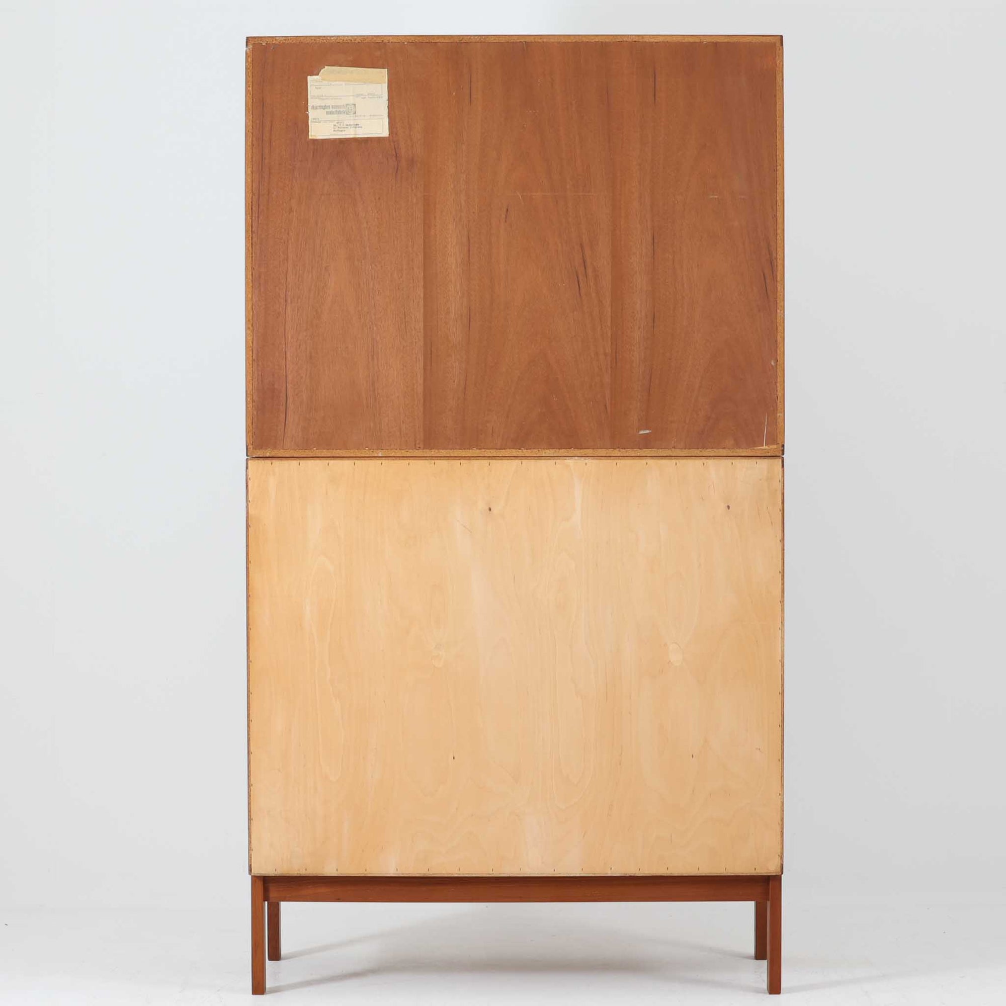 Bjerringbro Savvaerkによるチーク材キャビネットは、上下に分かれた構成と可動棚を備えた収納力の高さが魅力です。上段は3段のシェルフ、下段は珍しいポケットドア構造の扉内にA4サイズの書類が収納可能な引き出し型トレイが8段並び、書類や小物の整理に適しています。直線的で端正なフォルムと、チーク材の木目が美しく調和した佇まいは、北欧ビンテージらしい実用性と美しさを兼ね備えた逸品です。