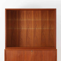 Bjerringbro Savvaerkによるチーク材キャビネットは、上下に分かれた構成と可動棚を備えた収納力の高さが魅力です。上段は3段のシェルフ、下段は珍しいポケットドア構造の扉内にA4サイズの書類が収納可能な引き出し型トレイが8段並び、書類や小物の整理に適しています。直線的で端正なフォルムと、チーク材の木目が美しく調和した佇まいは、北欧ビンテージらしい実用性と美しさを兼ね備えた逸品です。