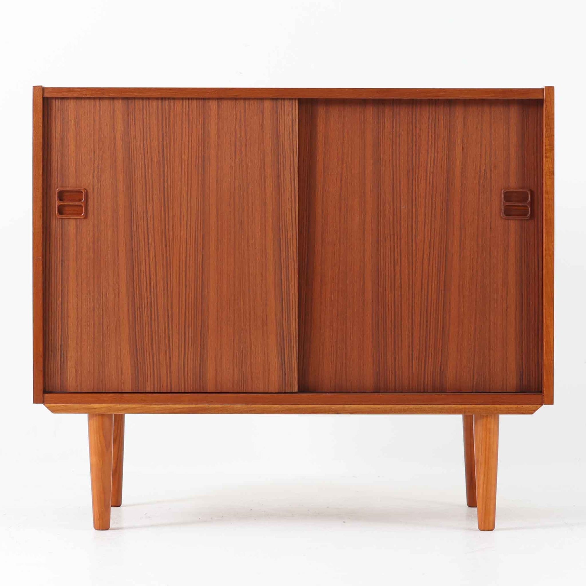 幅88cmとコンパクトなサイズ感が魅力のこちらのボードは、チーク材の温もりある質感と直線的なデザインが調和した北欧ビンテージ品です。前面にはスライド扉を備え、内部は左右に仕切られた収納スペースで、日用品の整理や見せたくない物の収納にも最適です。脚部にはテーパー加工が施され、軽やかな印象を与えつつ安定感も確保。省スペースに置けるため、玄関や寝室など限られた空間にもフィットし、日常に使いやすい一台です。