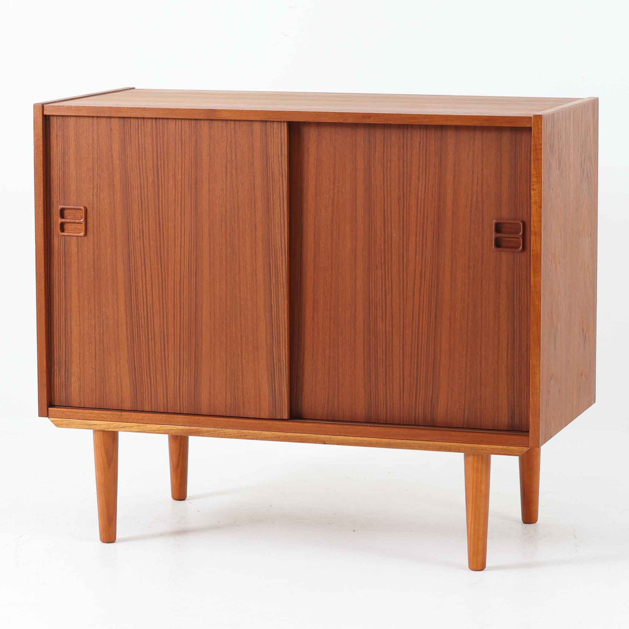 幅88cmとコンパクトなサイズ感が魅力のこちらのボードは、チーク材の温もりある質感と直線的なデザインが調和した北欧ビンテージ品です。前面にはスライド扉を備え、内部は左右に仕切られた収納スペースで、日用品の整理や見せたくない物の収納にも最適です。脚部にはテーパー加工が施され、軽やかな印象を与えつつ安定感も確保。省スペースに置けるため、玄関や寝室など限られた空間にもフィットし、日常に使いやすい一台です。