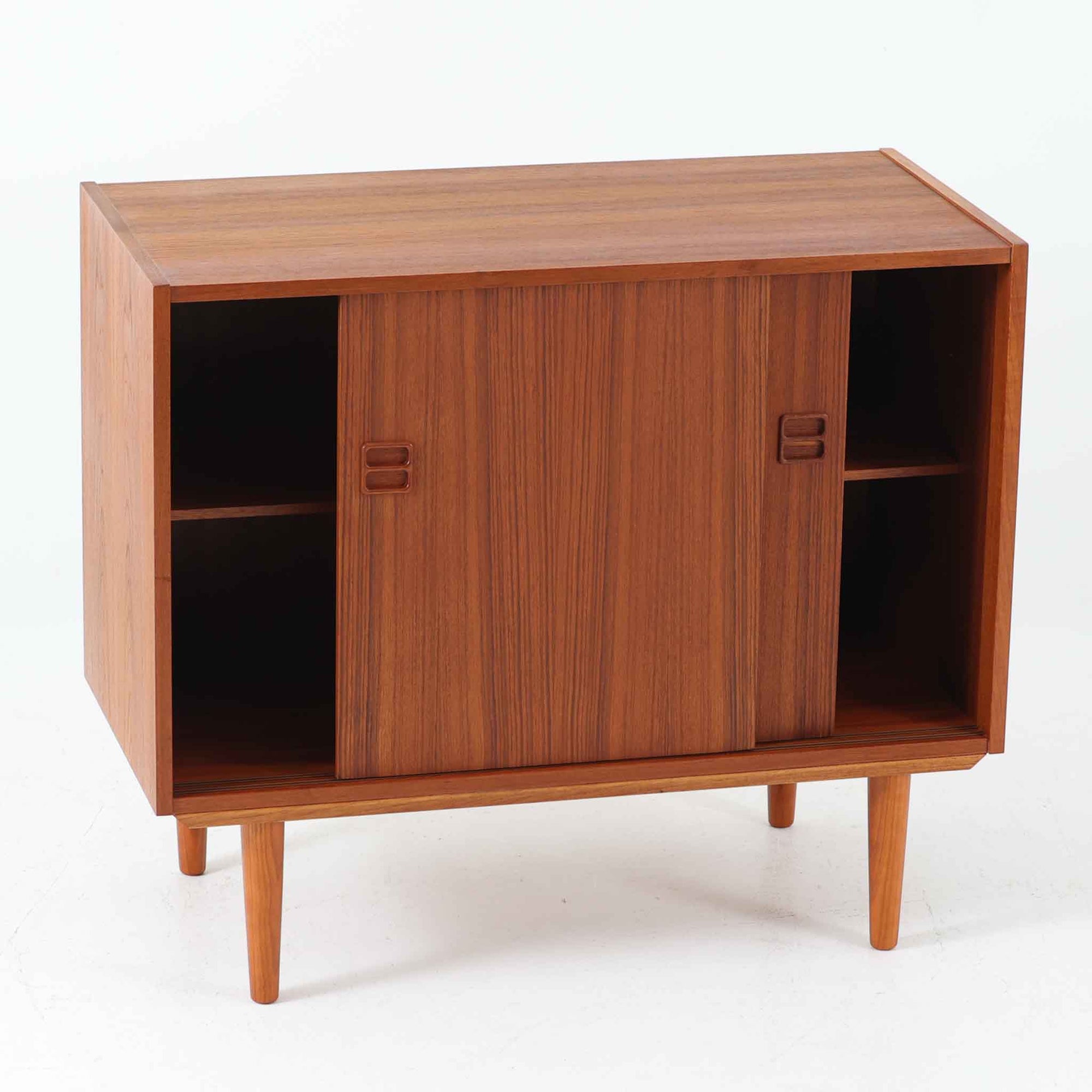 幅88cmとコンパクトなサイズ感が魅力のこちらのボードは、チーク材の温もりある質感と直線的なデザインが調和した北欧ビンテージ品です。前面にはスライド扉を備え、内部は左右に仕切られた収納スペースで、日用品の整理や見せたくない物の収納にも最適です。脚部にはテーパー加工が施され、軽やかな印象を与えつつ安定感も確保。省スペースに置けるため、玄関や寝室など限られた空間にもフィットし、日常に使いやすい一台です。