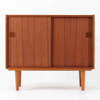 幅88cmとコンパクトなサイズ感が魅力のこちらのボードは、チーク材の温もりある質感と直線的なデザインが調和した北欧ビンテージ品です。前面にはスライド扉を備え、内部は左右に仕切られた収納スペースで、日用品の整理や見せたくない物の収納にも最適です。脚部にはテーパー加工が施され、軽やかな印象を与えつつ安定感も確保。省スペースに置けるため、玄関や寝室など限られた空間にもフィットし、日常に使いやすい一台です。