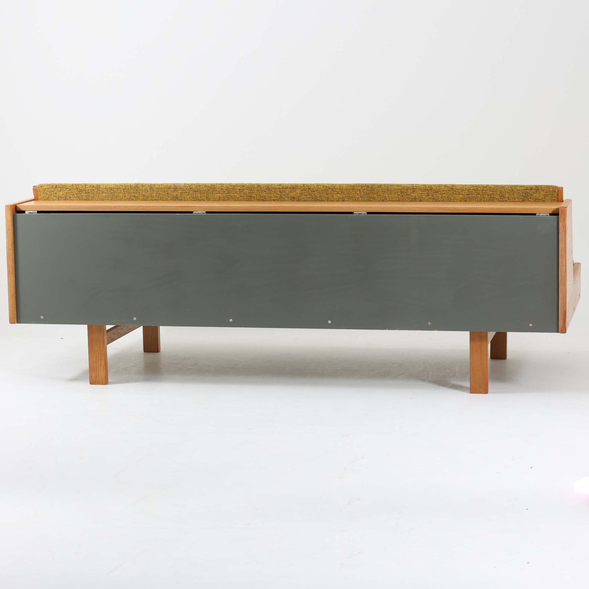 Hans J. WegnerがGetamaのために手掛けたGE258デイベッド。オーク材の端正な木肌と角脚による直線的で静かな佇まいが美しく、無駄を削ぎ落とした構造美にウェグナーらしい機能性が宿ります。背もたれを倒すことでベッドとしても使用できる実用的な設計で、ソファとしてリビングに置くのはもちろん、書斎やゲストルームでの簡易ベッドとしても活躍。経年により深まった木味とGetamaらしい堅牢なつくりが、北欧ビンテージならではの存在感と希少性を感じさせる一台です。