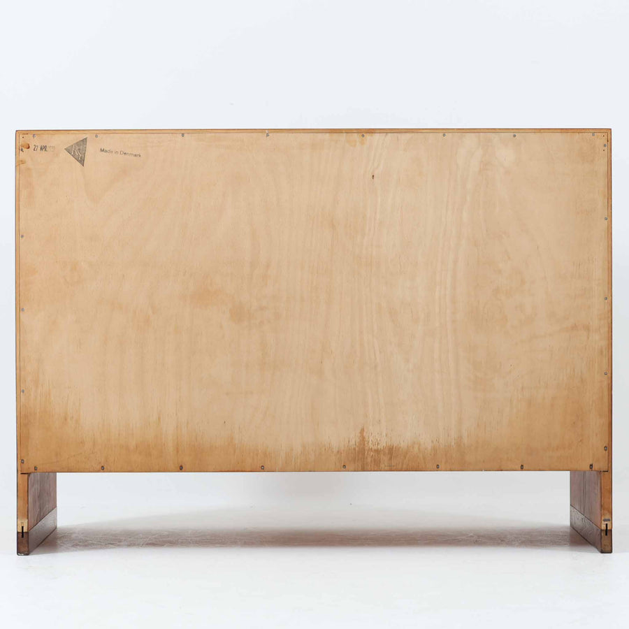 Hans J. Wegner（ハンス・J・ウェグナー）によってデザインされ、RY Mobler社により製造されたこちらのキャビネットは、美しいチーク材と実用的な構造が融合した北欧ビンテージ家具の名作です。扉にはチーク材特有の深い木目が活かされ、中央の控えめな金属製ハンドルがアクセントとなっています。内部は可動棚付きの2室構成で、食器類や書類、小物の整理にも適した収納力を備えています。注目すべきは、足摺にあたる下部のパーツにオーク材が使用されている点で、異なる木材の組み合わせが上質なコントラストを生み出しています。背面には「RY」ロゴと「27 APR 1959」のスタンプが残っており、当時のオリジナルであることが確認できます。リビングやダイニング、書斎などさまざまな空間で、温もりと凛とした佇まいを演出してくれる北欧ビンテージ家具らしい一台です。