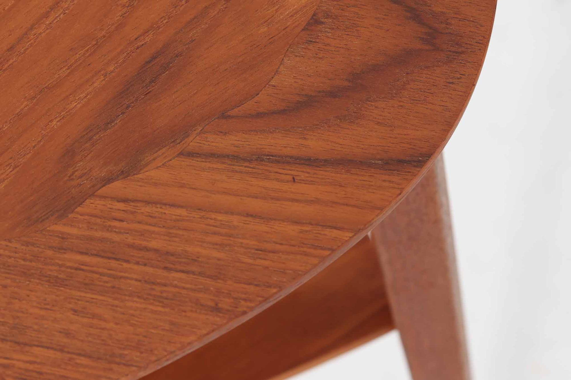 Holger Georg Jensen（ホルガー・ジョージ・イェンセン）によってデザインされ、Kubus moblerから製造されたデンマーク製ビンテージのサイドテーブルです。有機的な曲線を描く天板と、それを支える3本脚の構造が美しいバランスを保っています。天板下には同形状の棚板が設けられており、雑誌や小物の収納にも便利です。素材には艶やかなチーク材が用いられ、天板の木目の美しさも際立っています。北欧モダンを感じさせる上品な佇まいで、ソファサイドやベッドサイドにおすすめの一台です。