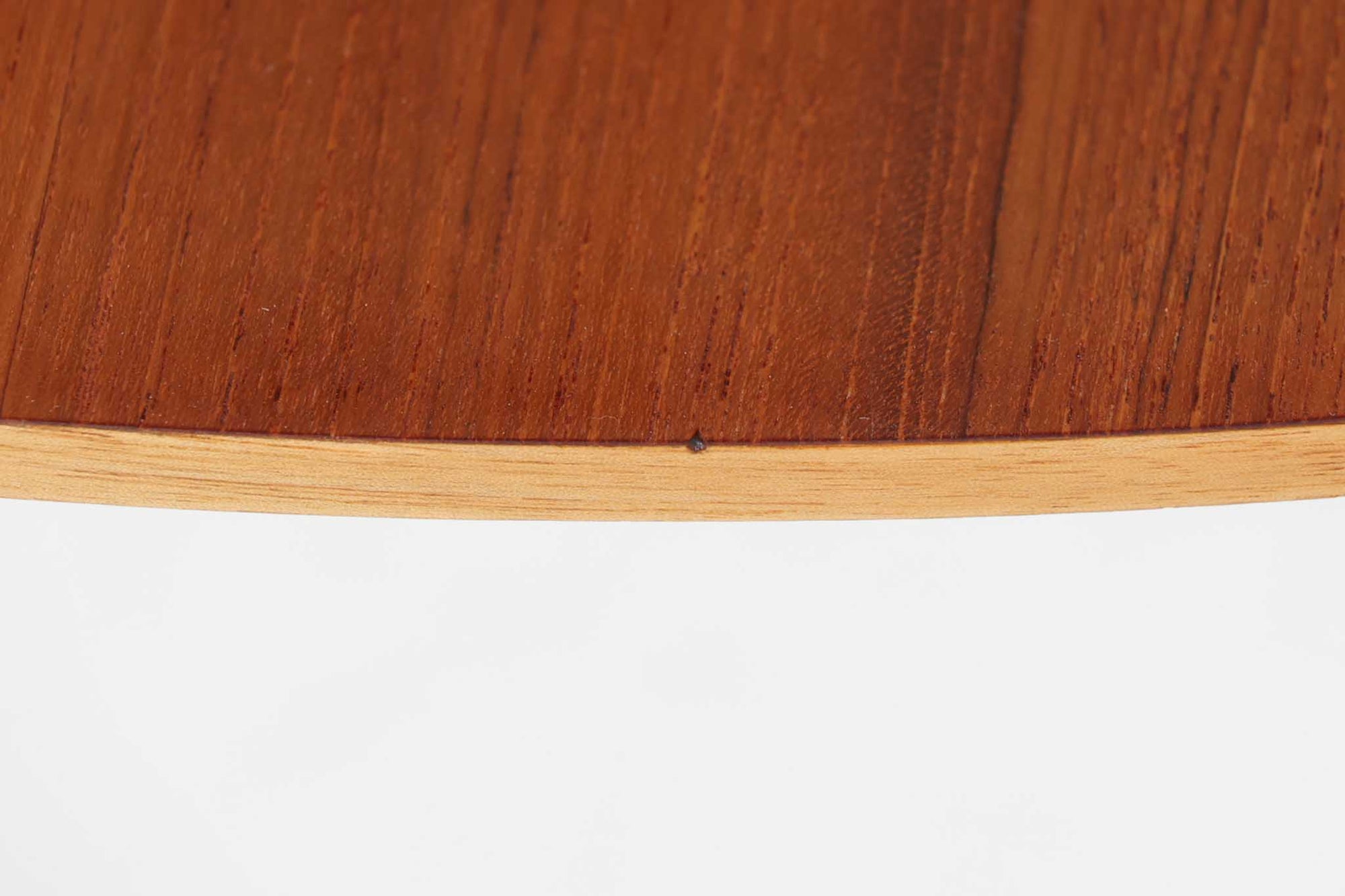 Holger Georg Jensen（ホルガー・ジョージ・イェンセン）によってデザインされ、Kubus moblerから製造されたデンマーク製ビンテージのサイドテーブルです。有機的な曲線を描く天板と、それを支える3本脚の構造が美しいバランスを保っています。天板下には同形状の棚板が設けられており、雑誌や小物の収納にも便利です。素材には艶やかなチーク材が用いられ、天板の木目の美しさも際立っています。北欧モダンを感じさせる上品な佇まいで、ソファサイドやベッドサイドにおすすめの一台です。