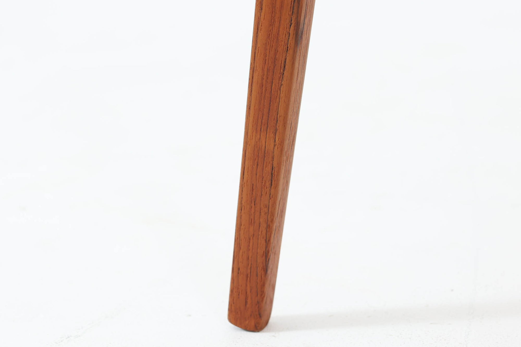 Holger Georg Jensen（ホルガー・ジョージ・イェンセン）によってデザインされ、Kubus moblerから製造されたデンマーク製ビンテージのサイドテーブルです。有機的な曲線を描く天板と、それを支える3本脚の構造が美しいバランスを保っています。天板下には同形状の棚板が設けられており、雑誌や小物の収納にも便利です。素材には艶やかなチーク材が用いられ、天板の木目の美しさも際立っています。北欧モダンを感じさせる上品な佇まいで、ソファサイドやベッドサイドにおすすめの一台です。