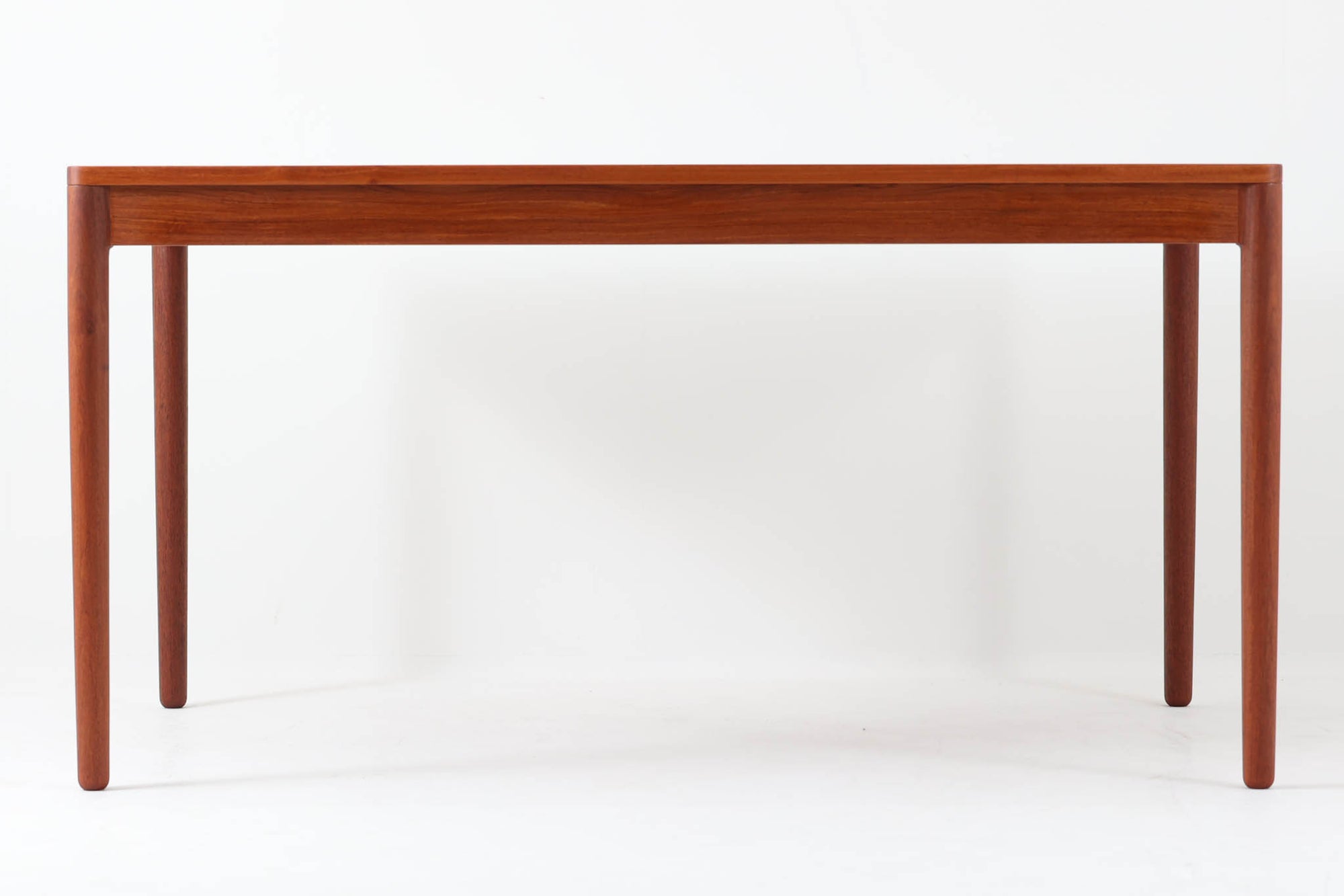 デンマーク製のダイニングテーブル。脚が固定された珍しいデザインで、上質なチーク材を贅沢に使用し、温かみのある色合いと美しい木目が特徴です。シンプルで洗練された細身の脚部は、接合部が特に美しく、北欧家具職人の高い技術が感じられます。装飾を排したミニマルなデザインながら、適度な厚みの天板が重厚感と軽やかさを兼ね備えています。4～6人用のサイズで、ダイニングテーブルとしてはもちろん、書斎デスクやワークテーブルとしても幅広く活用できる、汎用性の高い一品です。