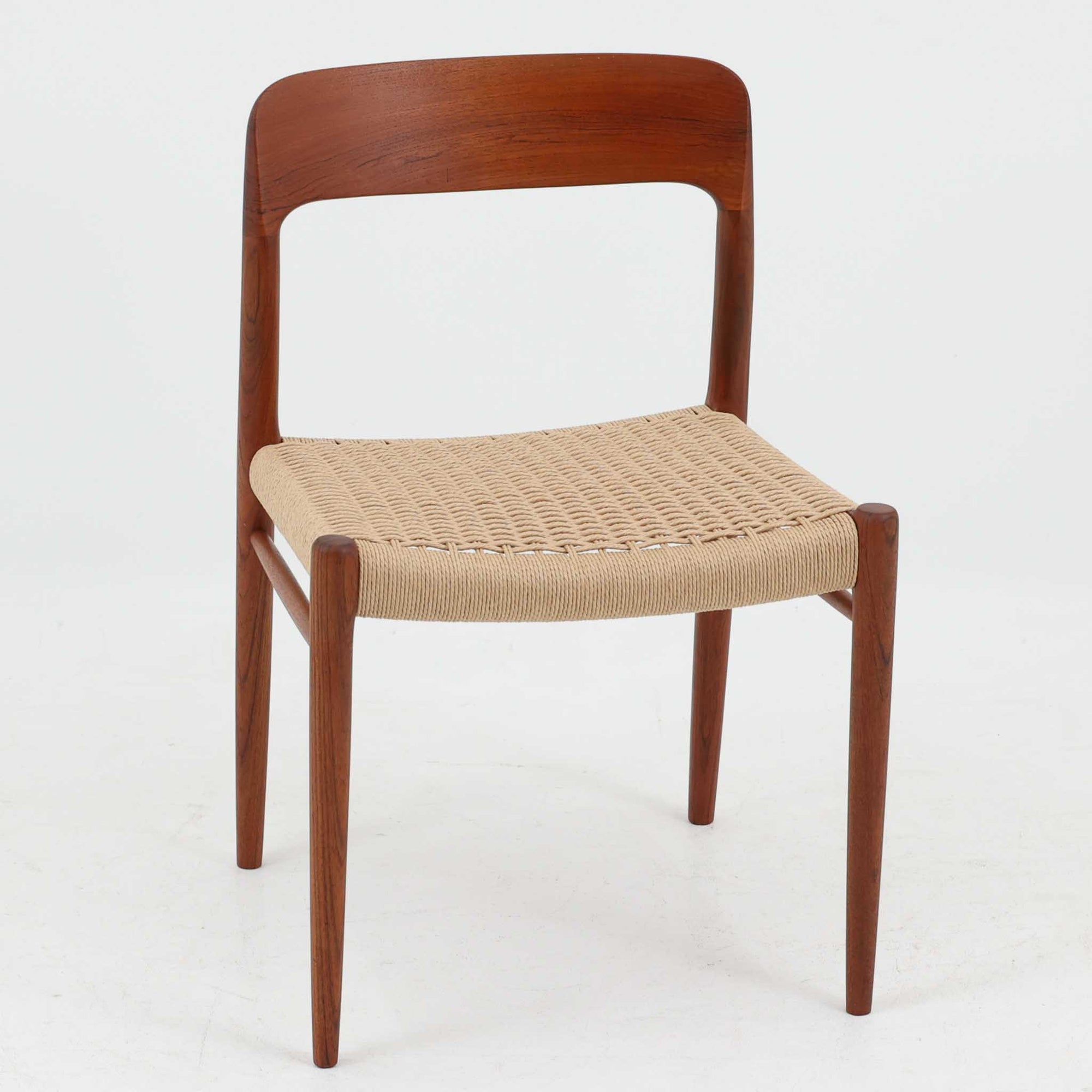 Niels O. MollerによるModel 75 ダイニングチェア。美しい曲線を描く背もたれと、繊細なラインで構成されたフレームが印象的な北欧デザインです。チーク材ならではの深みある木目と、丁寧に編み込まれたペーパーコード座面が調和し、軽やかさと上質感を兼ね備えています。背中をやさしく支える有機的なフォルムと高い職人技が感じられる構造で、ダイニングはもちろん書斎や空間のアクセントチェアとしても活躍。経年変化による味わいも魅力の北欧ビンテージを代表する一脚です。