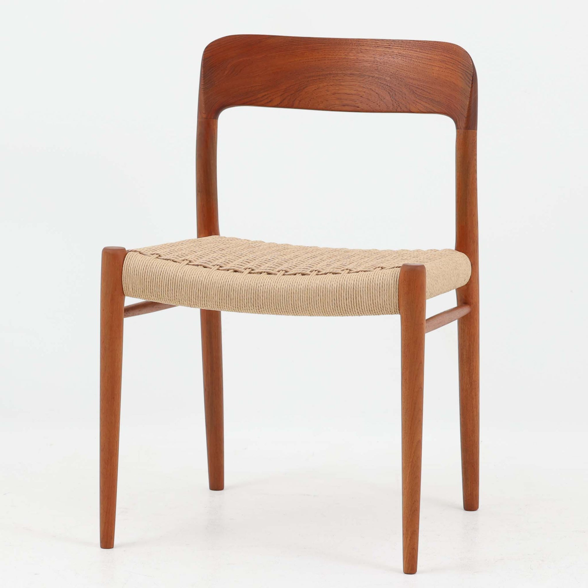 Niels O. MollerによるModel 75 ダイニングチェア。美しい曲線を描く背もたれと、繊細なラインで構成されたフレームが印象的な北欧デザインです。チーク材ならではの深みある木目と、丁寧に編み込まれたペーパーコード座面が調和し、軽やかさと上質感を兼ね備えています。背中をやさしく支える有機的なフォルムと高い職人技が感じられる構造で、ダイニングはもちろん書斎や空間のアクセントチェアとしても活躍。経年変化による味わいも魅力の北欧ビンテージを代表する一脚です。