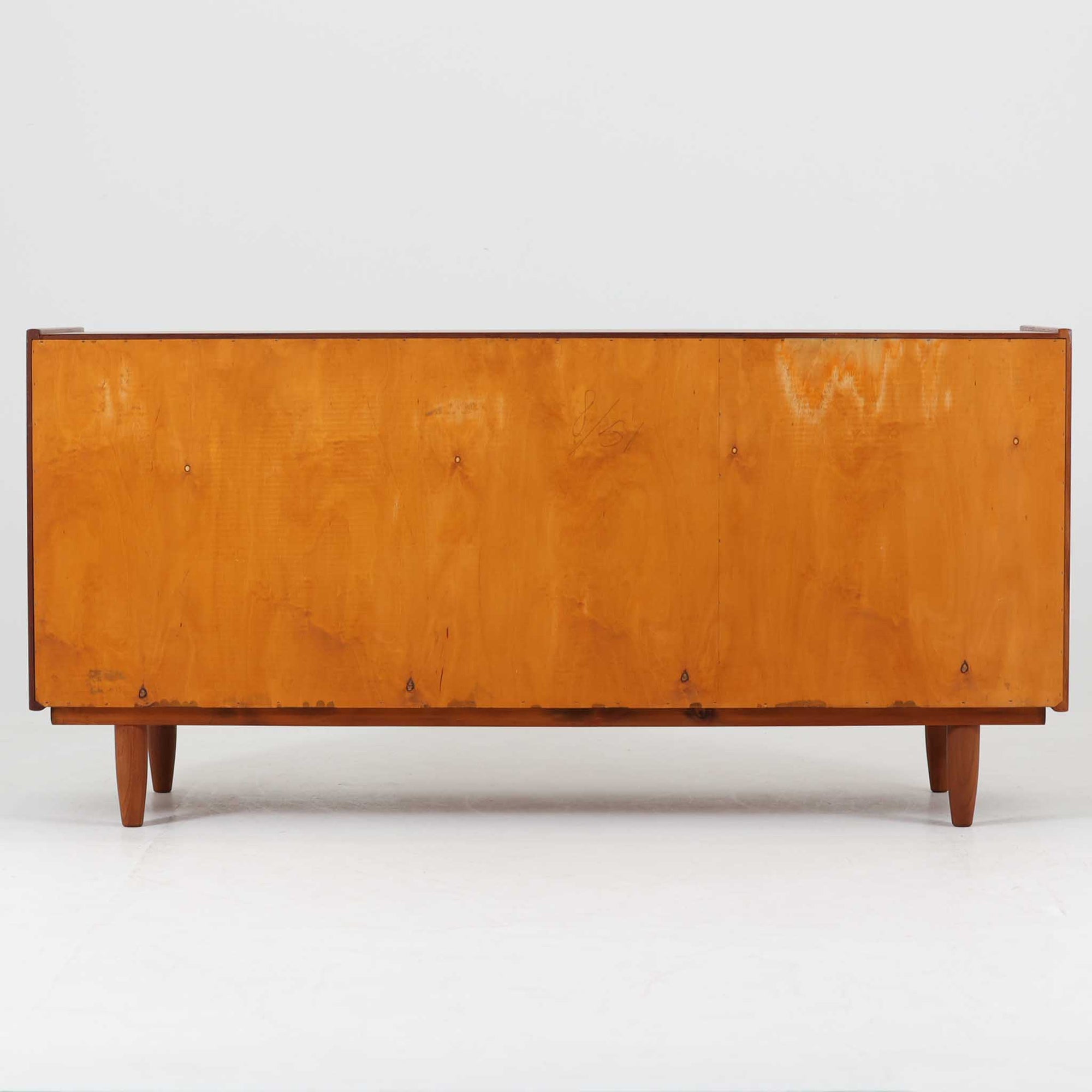チーク材の美しい木目と滑らかな質感が際立つこちらのローボードは、収納力とデザイン性を兼ね備えた北欧ビンテージ家具です。丸い指掛けが施された引き戸を開けると、内部には仕切り棚やトレイ付きの収納スペースがあり、食器類や小物の整理に最適です。脚部は丸脚で軽やかな印象を与え、リビングのテレビ台やキャビネットとしても活躍する一台です。年月を経て深まった風合いが、空間に温かみと落ち着きをもたらします。