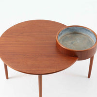 Arne Wahl Iversenがデザインし、Vinde Mobelfabrik社から製造されたユニークなプランター付きセンターテーブルは、チーク材の温かみと実用性を兼ね備えた北欧ビンテージの魅力あふれる一台です。天板の一部にメタル製の植栽スペースが組み込まれており、観葉植物や小物ディスプレイを楽しめる機能的な構造が特徴です。ラウンドフォルムに、スラリと伸びたテーパードレッグが軽やかさを加え、リビング空間に個性と洗練をもたらします。