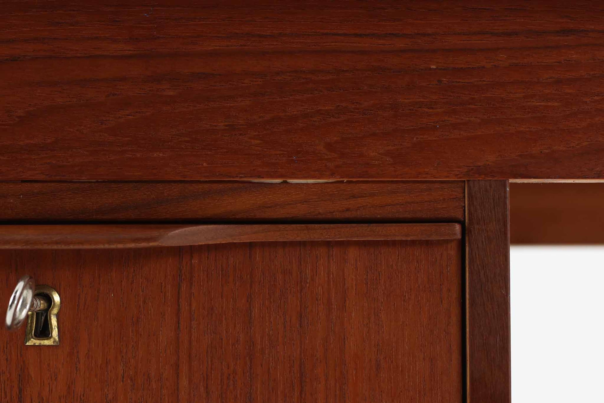 シンプルで洗練された佇まいが魅力のこちらの片袖デスクは、上質なチーク材を用いた北欧ビンテージ家具です。丸みを帯びたテーパードレッグや、緩やかにカーブした引き出しの取っ手が、温もりと職人技を感じさせるディテールとなっています。引き出しは3段構成で収納力があり、鍵付きの上段は大切な書類の保管にも最適です。コンパクトながら実用性に優れており、ワークデスクやドレッサー代わりとしてもおすすめできる逸品です。経年変化による木肌の風合いもビンテージならではの魅力で、空間に落ち着きと品格を与えてくれます。