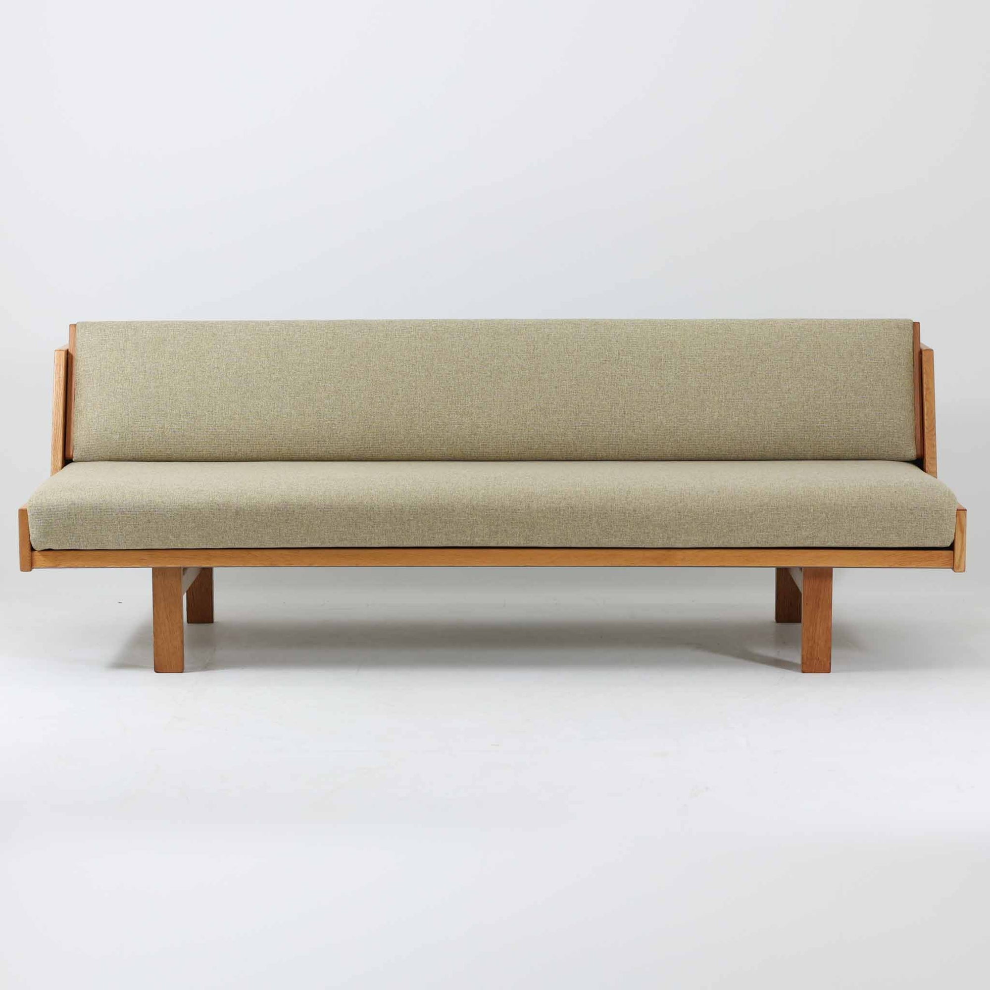 Hans J. WegnerがGetamaのためにデザインしたGE258デイベッド。オーク材の明るく上品な木肌と角脚の端正なフォルムが美しく、直線を基調としたミニマルな構造にウェグナーらしい機能美が息づいています。背もたれを倒すことでベッドとしても使用できる実用的な設計で、リビングでは洗練されたソファ、書斎やゲストルームでは簡易ベッドとしても活躍。経年により深まったオークの味わいとGetamaならではの堅牢なつくりが、北欧ビンテージらしい存在感と希少性を高める一台です。