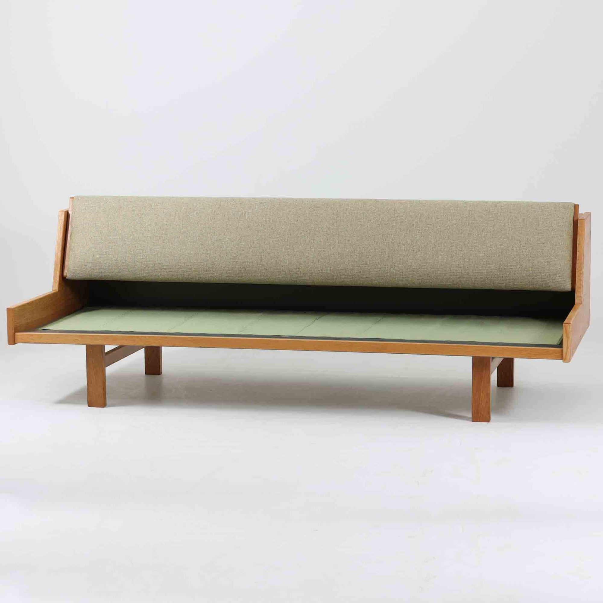 Hans J. WegnerがGetamaのためにデザインしたGE258デイベッド。オーク材の明るく上品な木肌と角脚の端正なフォルムが美しく、直線を基調としたミニマルな構造にウェグナーらしい機能美が息づいています。背もたれを倒すことでベッドとしても使用できる実用的な設計で、リビングでは洗練されたソファ、書斎やゲストルームでは簡易ベッドとしても活躍。経年により深まったオークの味わいとGetamaならではの堅牢なつくりが、北欧ビンテージらしい存在感と希少性を高める一台です。