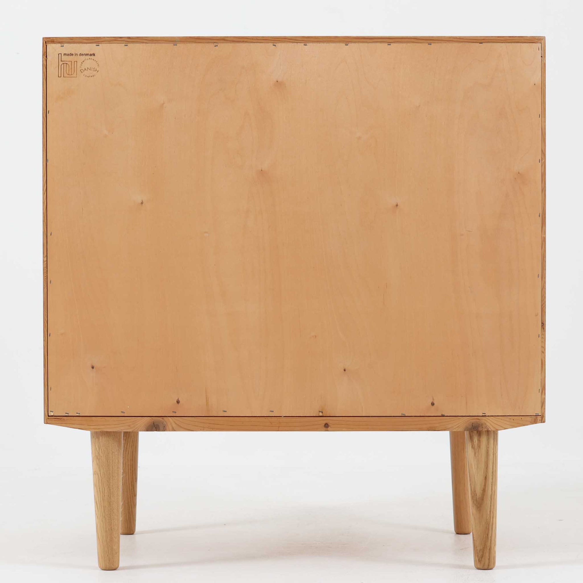 Poul Hundevadがデザインし、Hundevad &amp; Co社から製造されたこちらのキャビネットは、上質なオーク材を用いた小ぶりな北欧ビンテージ品で、すっきりとした面構えと繊細な脚部が印象的な一台です。鍵付きの開き戸を備え、内部には棚板が設けられており、収納家具としての実用性に加え、空間にナチュラルで落ち着いた佇まいをもたらします。なお、脚部は後年に交換されている可能性がありますが、全体の雰囲気を損なわない自然な仕上がりです。
