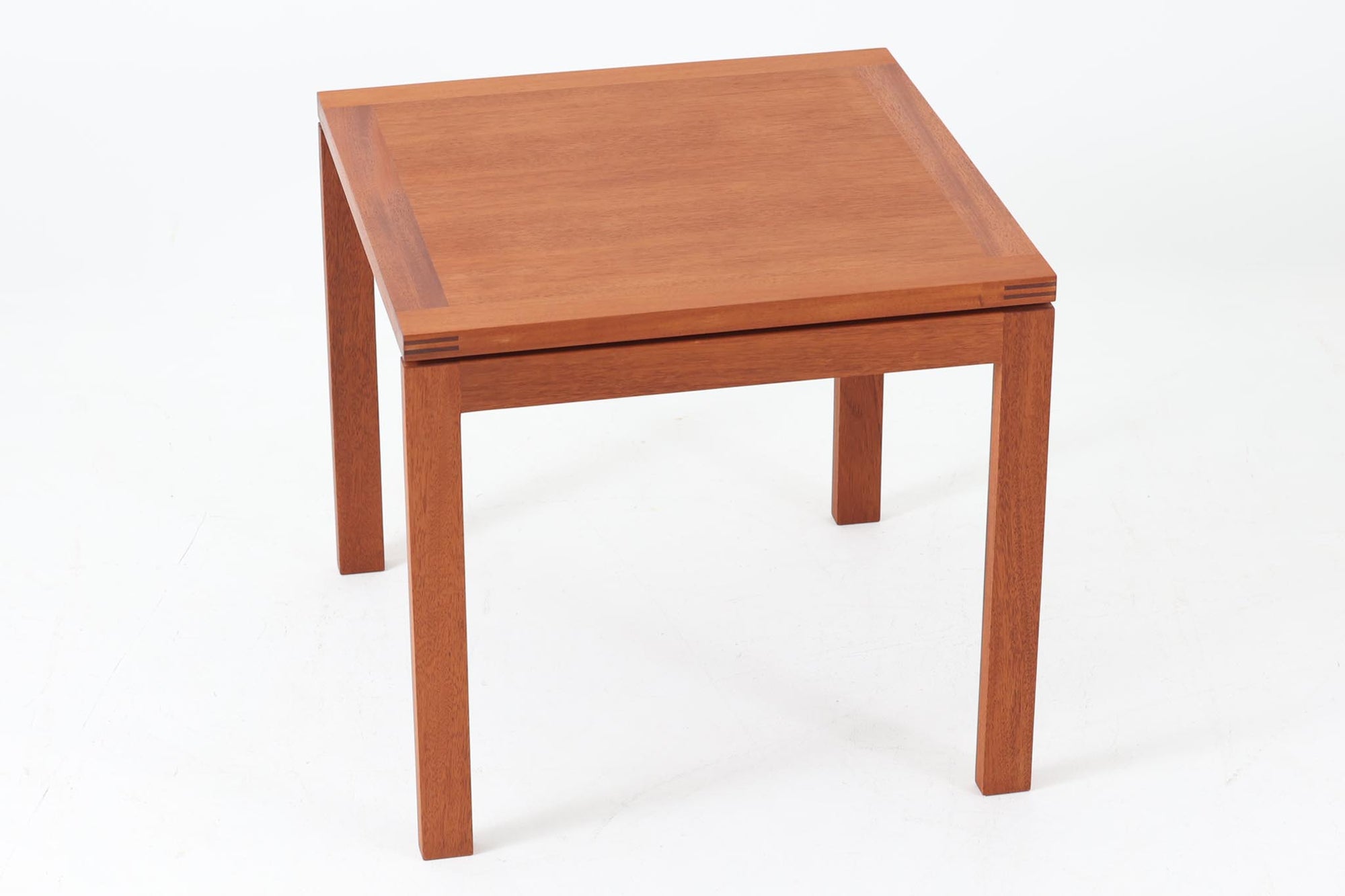 デンマークの老舗家具メーカー、munch mobler社製、Henning Jensen &amp; Torben Valeurによるデザインの北欧ビンテージテーブルです。上質なマホガニー材を使用し、滑らかな木肌と深みのある赤褐色の色合いが上品な佇まいを演出します。天板と脚部には美しい留め加工が施されており、シンプルな構造の中に職人技が光るディテールが際立ちます。幅60cm×奥行60cmのサイズ感は、ソファサイドに置くサイドテーブルとしても、リビング中央でのセンターテーブルとしても使い勝手が良く、さまざまなシーンにフィットします。ミニマルでありながらも個性を感じさせる一台をお探しの方におすすめです。