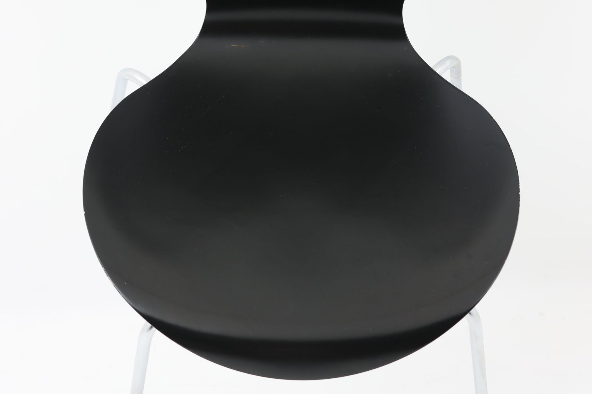 デンマークの名門Fritz Hansen社製、アルネ・ヤコブセンによる名作「セブンチェア」。こちらは2007年に製造された比較的新しいモデルです。成形合板による流れるようなフォルムが特徴で、背もたれから座面へと続く美しいカーブが、快適な座り心地を提供します。ブラックのシェルとクロームメッキの脚がモダンで洗練された印象を演出し、どんな空間にも調和するデザインです。