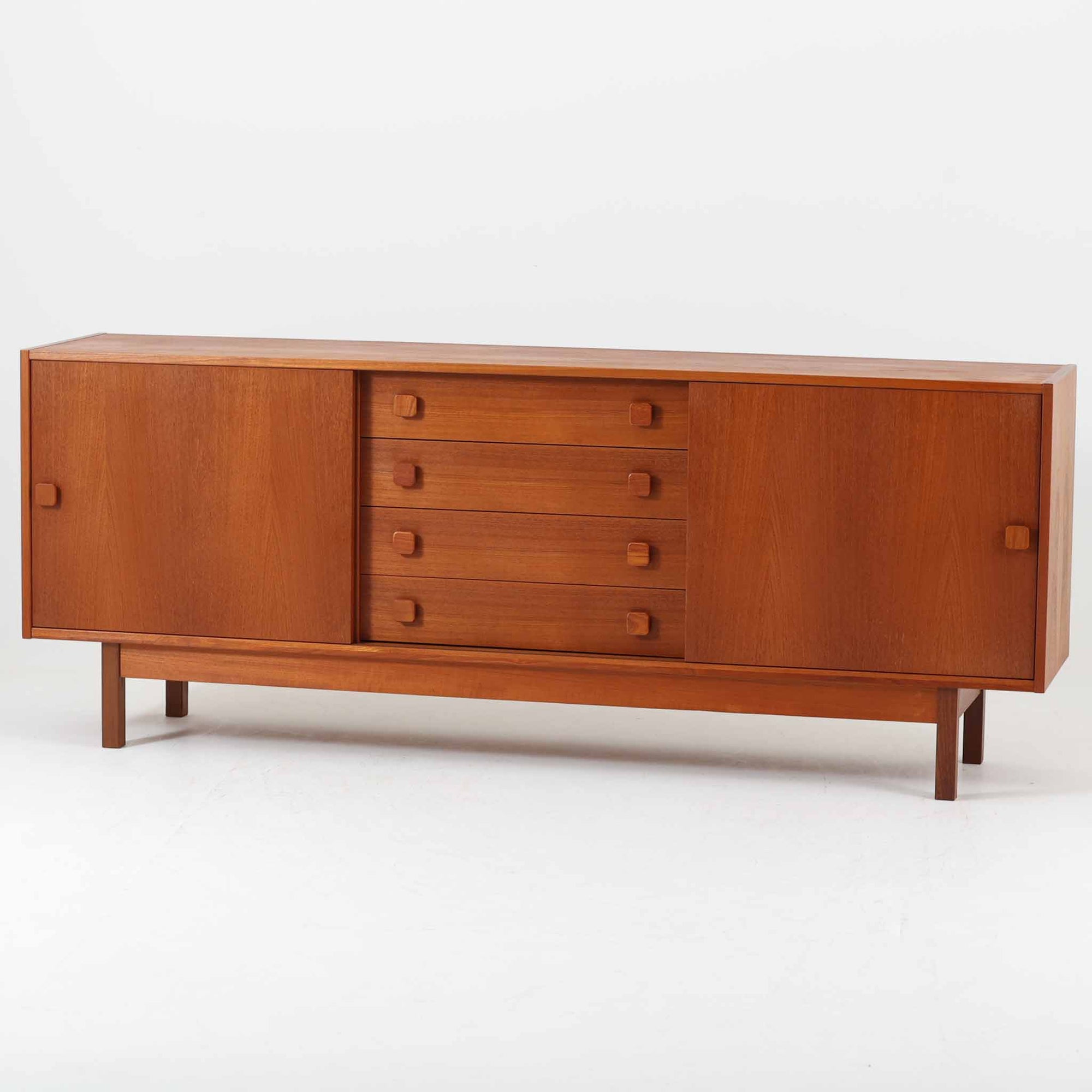 Domino Mobler社製の幅182cmのボードは、上質なチーク材を用いた美しい木目と、左右の開き戸と中央の引き出しという機能的な構成が魅力の北欧ビンテージ家具です。丸みのあるスクエア取手や脚部のすっきりとしたラインが、端正なフォルムを引き立てつつ温かみも感じさせます。収納力にも優れ、リビングやダイニングで食器や日用品を収めるサイドボードとしてはもちろん、テレビボードとしても活躍する汎用性の高い一台です。