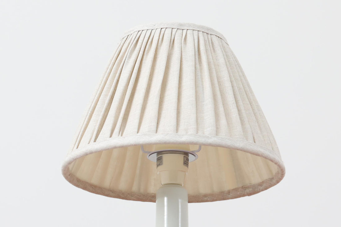 デンマークRoyal Copenhagen製、Ellen malmerデザインによるテーブルランプ。1969〜1974年に製造されたFajanceシリーズの一点で、花を思わせる有機的なモチーフが温かみのある印象を与えます。艶のある白地に手描きで施された装飾が映え、コンパクトながらも空間のアクセントになる存在感があります。シェードは新品のリネン製です。