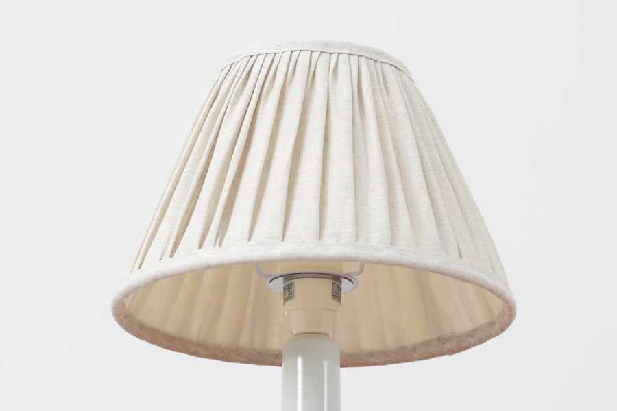 デンマークRoyal Copenhagen製、Ellen malmerデザインによるテーブルランプ。1969〜1974年に製造されたFajanceシリーズの一点で、花を思わせる有機的なモチーフが温かみのある印象を与えます。艶のある白地に手描きで施された装飾が映え、コンパクトながらも空間のアクセントになる存在感があります。シェードは新品のリネン製です。
