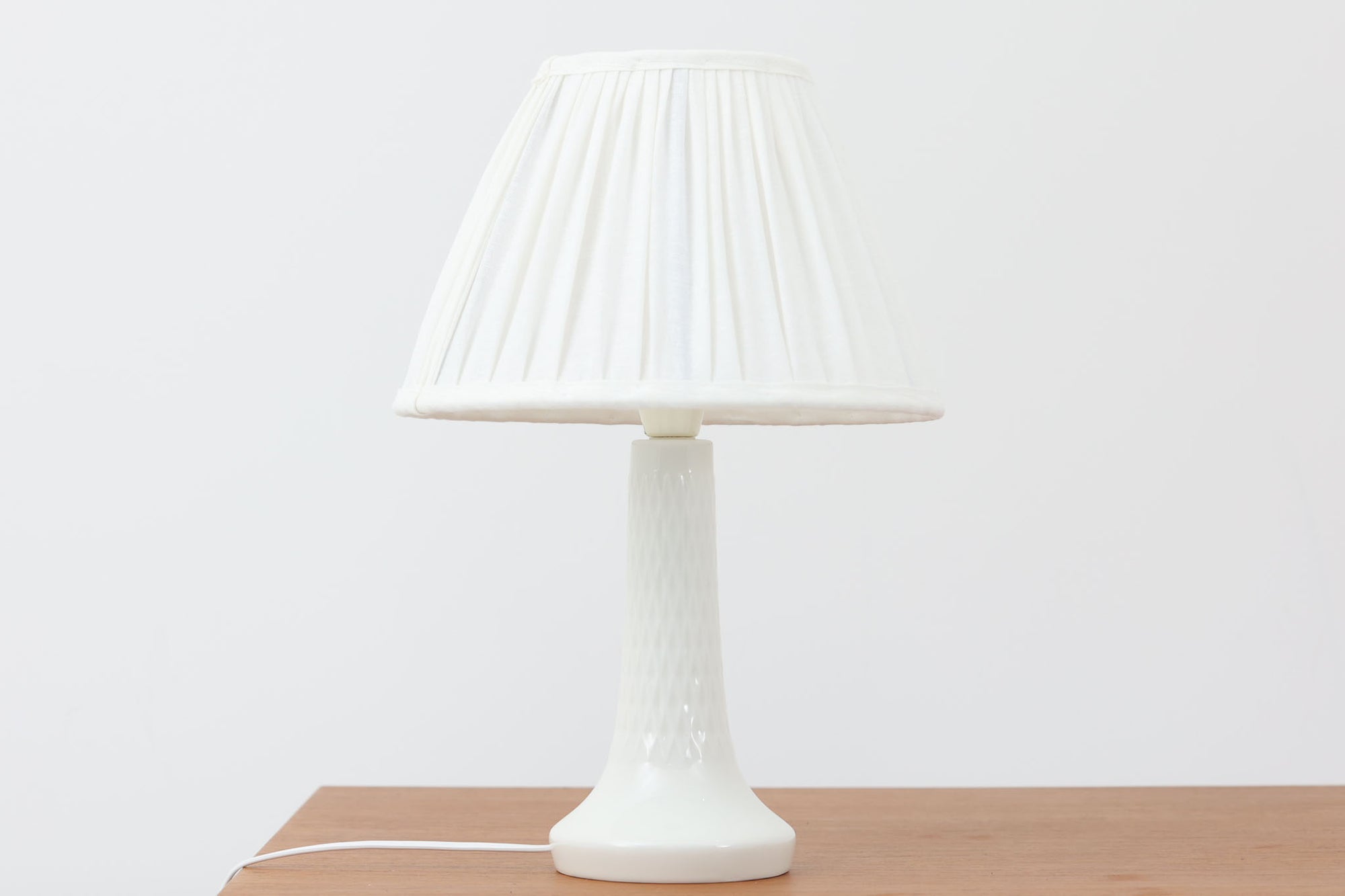 Royal CopenhagenがLe Klintのために製作したテーブルランプ。デザイナーはTorkil Olsen。艶のある白磁に繊細な凹凸模様が施され、上品でモダンな佇まいです。明るく清潔感のある印象で、どんな空間にも馴染みます。シェードには新品のリネン製を合わせており、やわらかな灯りが広がります。