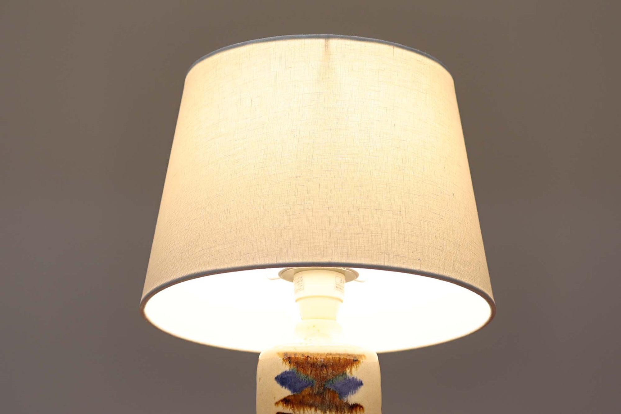 デンマークの名窯michael Andersen &amp; Sønによるテーブルランプ。アイボリートーンの陶器ボディにブルーやブラウンの幾何学模様が手描きであしらわれた美しい一点。光沢のある釉薬の表情も魅力的です。シェードは新品のリネン製に交換済み。
