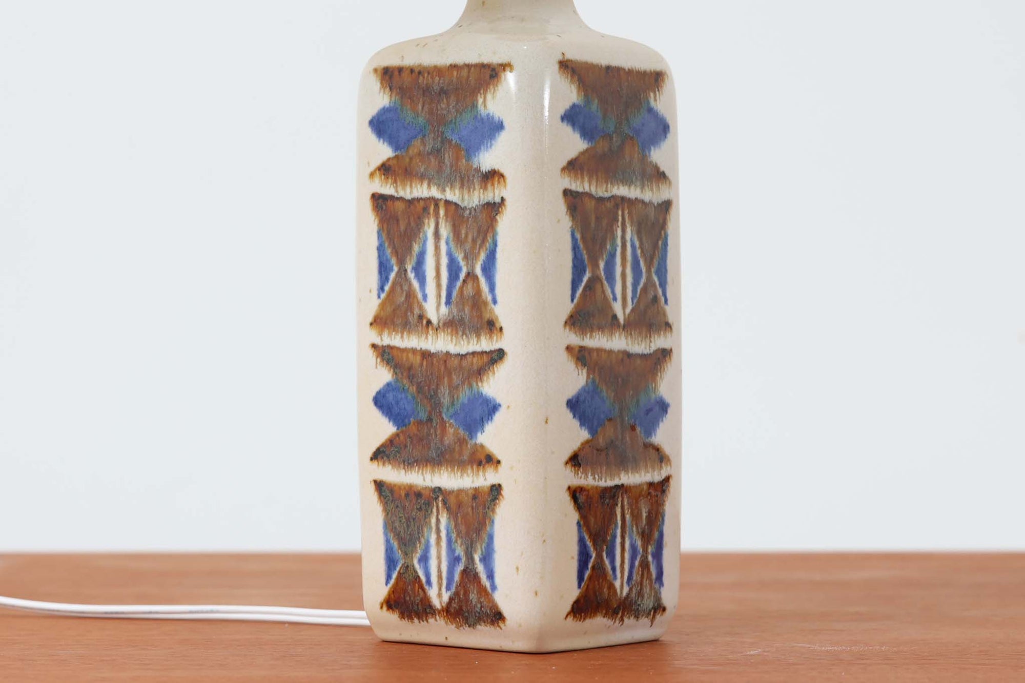 デンマークの名窯michael Andersen &amp; Sønによるテーブルランプ。アイボリートーンの陶器ボディにブルーやブラウンの幾何学模様が手描きであしらわれた美しい一点。光沢のある釉薬の表情も魅力的です。シェードは新品のリネン製に交換済み。