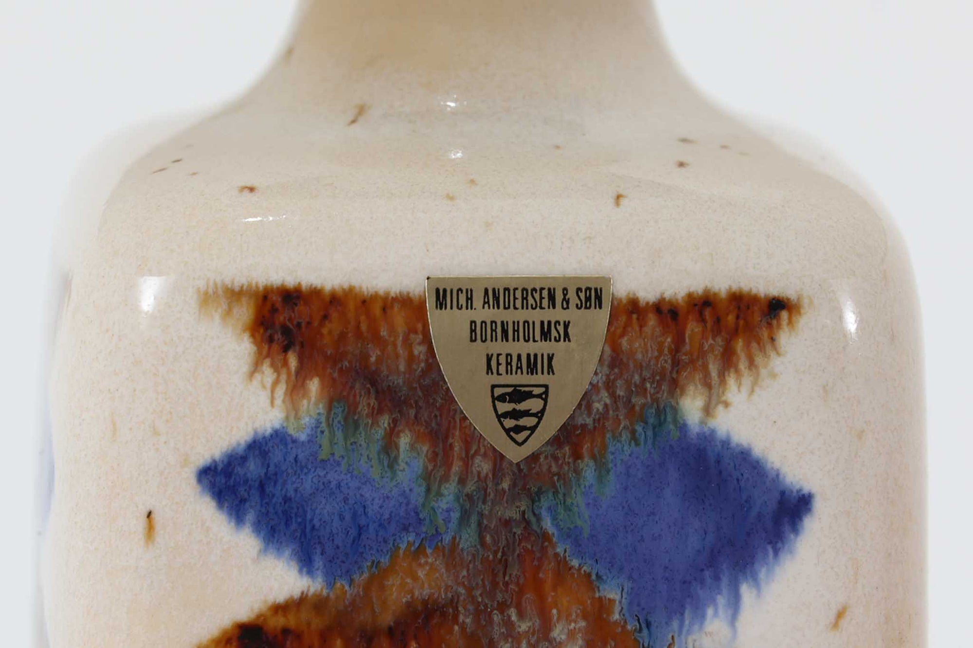 デンマークの名窯michael Andersen &amp; Sønによるテーブルランプ。アイボリートーンの陶器ボディにブルーやブラウンの幾何学模様が手描きであしらわれた美しい一点。光沢のある釉薬の表情も魅力的です。シェードは新品のリネン製に交換済み。