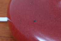 デンマークの照明ブランドLe Klint（レ・クリント）のテーブルランプで、デザイナーはOle Boggild（オーレ・ボギル）。艶やかなレッドの釉薬が美しく、ふっくらと丸みを帯びたフォルムが愛らしくも上品な印象を与えます。シェードはLe Klint社製ではありませんが、新品のリネン製プリーツシェードを合わせており、クラシカルな佇まいと柔らかな光を演出します。北欧らしい温かみと洗練された存在感を持ち、ベッドサイドやリビングのアクセントとして取り入れやすい一灯です。