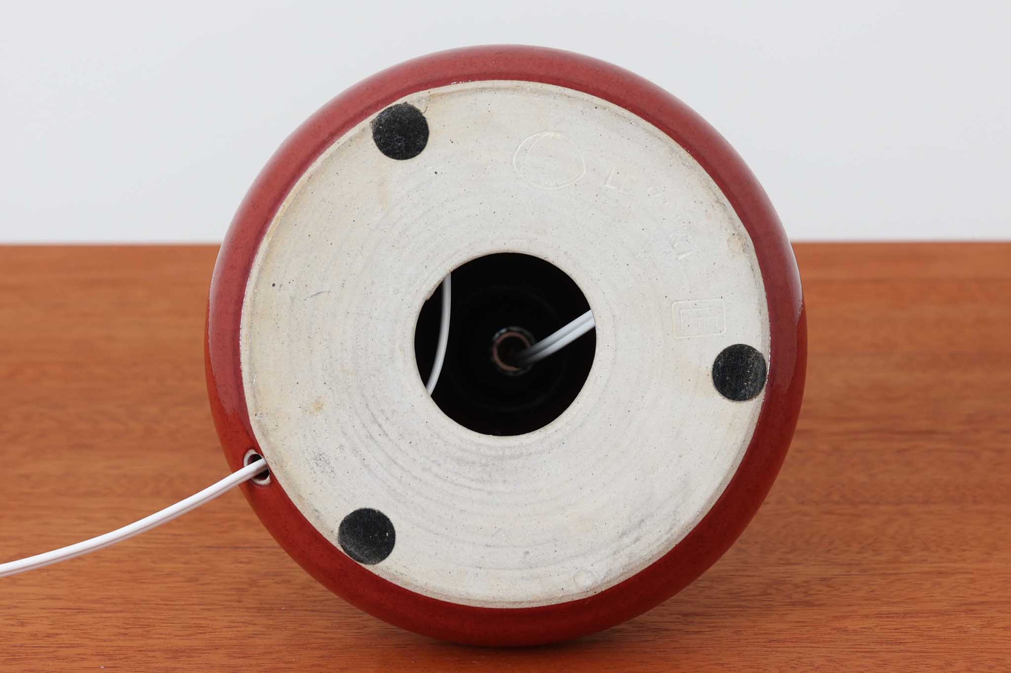 デンマークの照明ブランドLe Klint（レ・クリント）のテーブルランプで、デザイナーはOle Boggild（オーレ・ボギル）。艶やかなレッドの釉薬が美しく、ふっくらと丸みを帯びたフォルムが愛らしくも上品な印象を与えます。シェードはLe Klint社製ではありませんが、新品のリネン製プリーツシェードを合わせており、クラシカルな佇まいと柔らかな光を演出します。北欧らしい温かみと洗練された存在感を持ち、ベッドサイドやリビングのアクセントとして取り入れやすい一灯です。