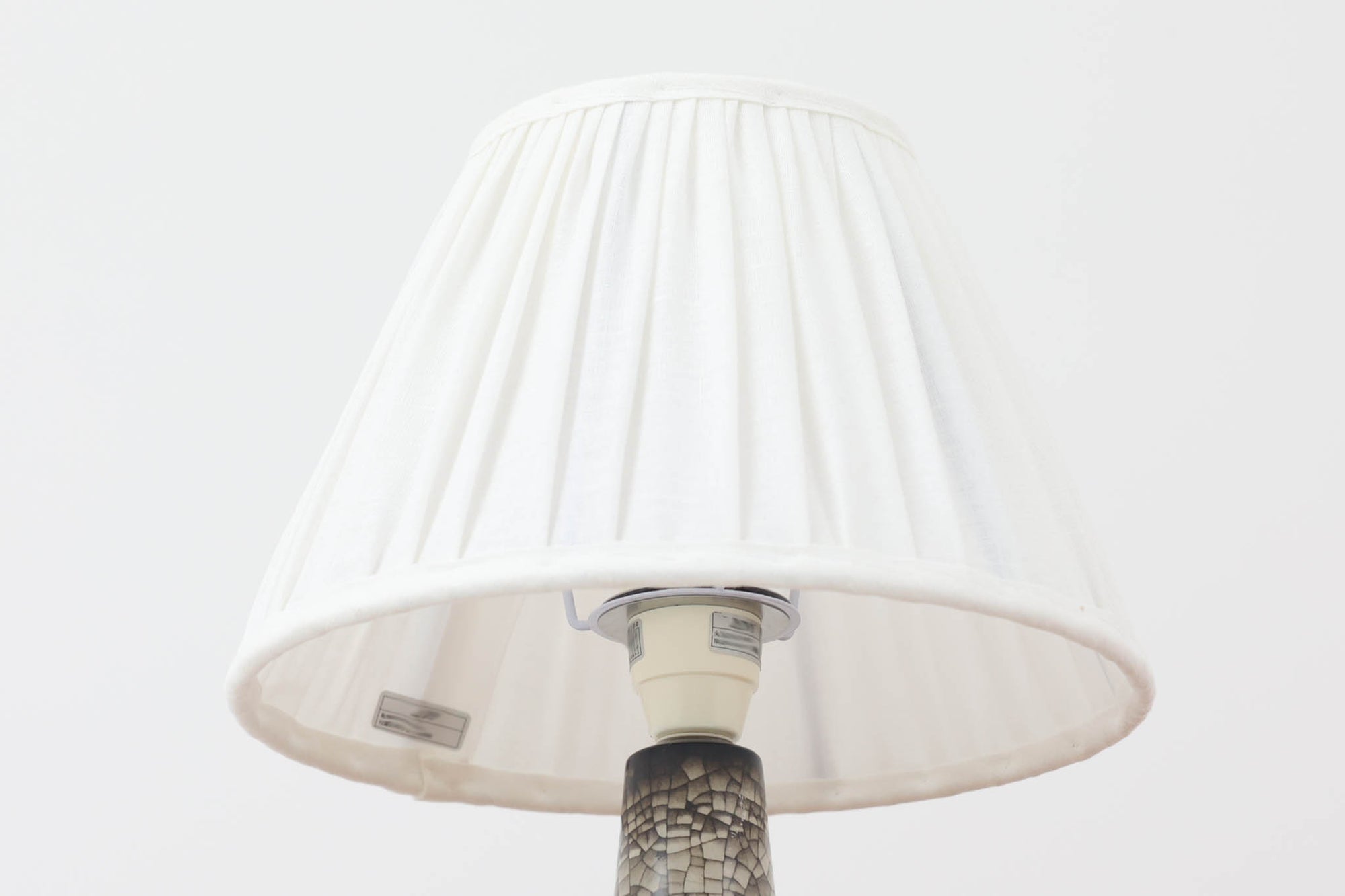 デンマーク・ボーンホルム島の老舗陶器メーカー、michael Andersen &amp; Sonによるテーブルランプ。細やかな貫入模様と深みのある釉薬の色合いが特徴で、ベース部分は温かみのあるクラフト感を漂わせています。シェードは新品のリネン製で、やさしく光を拡散し、空間に柔らかな雰囲気をもたらします。北欧ヴィンテージらしい造形美と素材感を楽しめる一点です。