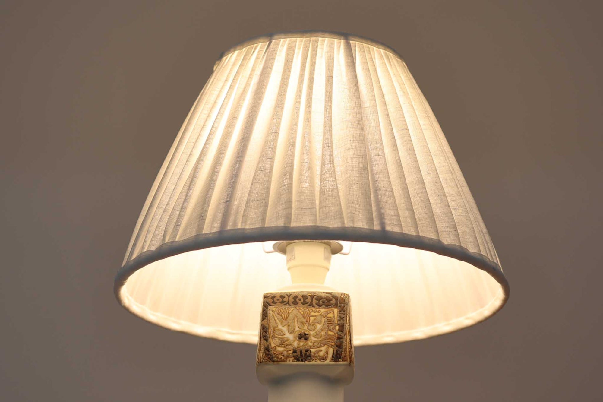 Royal Copenhagen製のベースが使用されたテーブルランプです。製造年数（1965〜1970年代）も少なく、現在では入手困難な希少モデルとなっています。現在の製造方法とは異なり、ファイアンス釜で作られた陶器ならではの独特な風合いが魅力で、ヴィンテージ品としての価値も高い一点です。ベースの柄は自然をモチーフとしたNils Thorssonによる人気のBACAシリーズで、職人の手作業によるフリーハンドで描かれているため、ひとつとして同じものが存在しない点もRoyal Copenhagenならではの魅力です。高さは約50cmとやや大きめで、インテリアのアクセントとしても存在感があり、オブジェのようにお部屋をおしゃれに演出してくれます。