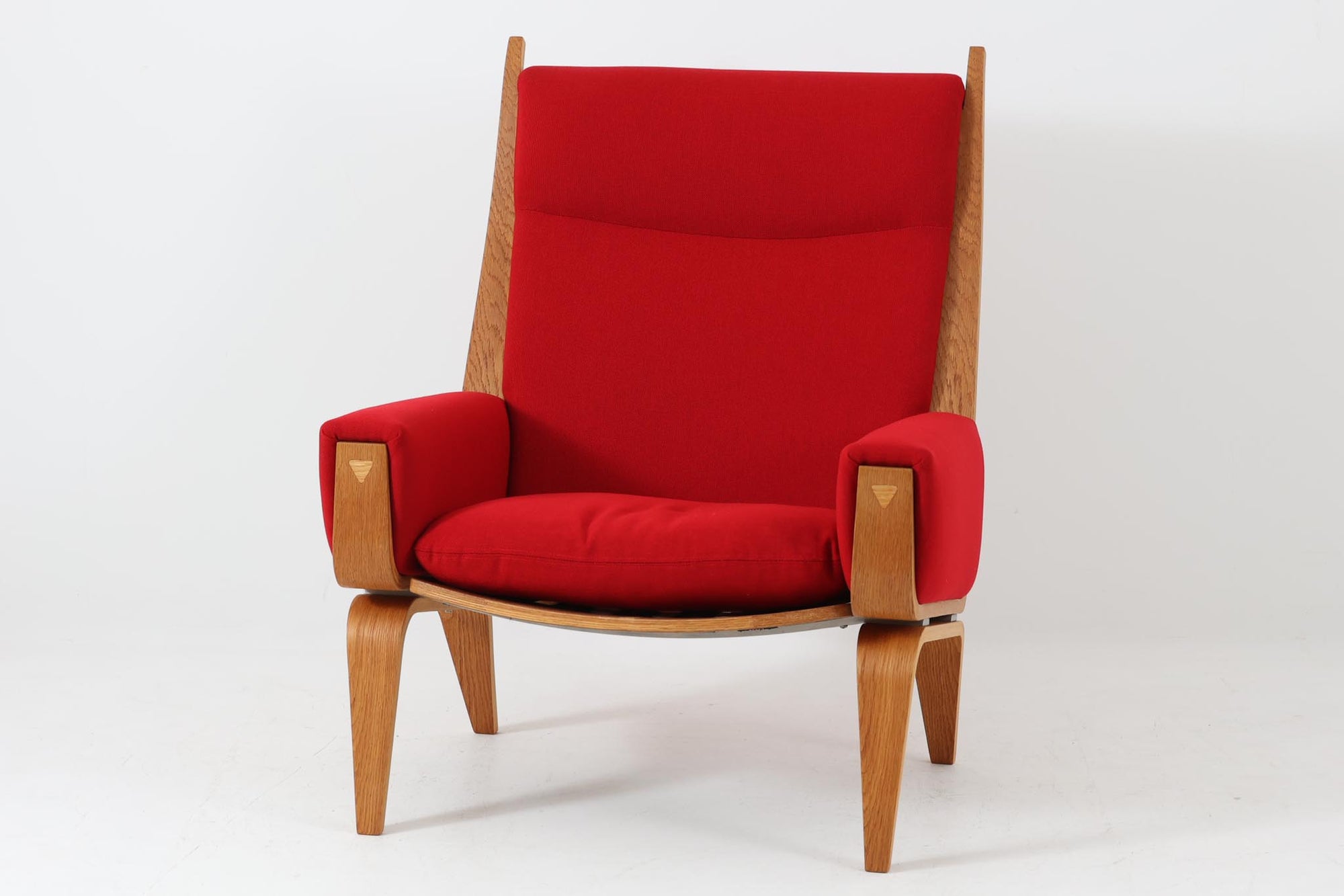 Hans J. Wegner（ハンス・J・ウェグナー）が1960年代にデザインし、Getama（ゲタマ）社によって製造されたGE501Aモデルのハイバックシングルソファ。当時としては珍しく、フレームにプライウッドが使用されています。フレームには堅牢で美しい木目を持つオーク材を使用し、直線と曲線が融合した造形が北欧家具らしい洗練された印象を与えます。張地には鮮やかな赤のファブリックを使用し、空間にアクセントを添えると同時に、快適性と耐久性も兼ね備えた仕上がりです。ヴィンテージならではの存在感と高い実用性を兼ね備えた一脚として、リビングや読書スペースに最適です。