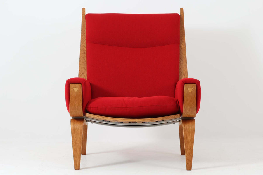 Hans J. Wegner（ハンス・J・ウェグナー）が1960年代にデザインし、Getama（ゲタマ）社によって製造されたGE501Aモデルのハイバックシングルソファ。当時としては珍しく、フレームにプライウッドが使用されています。フレームには堅牢で美しい木目を持つオーク材を使用し、直線と曲線が融合した造形が北欧家具らしい洗練された印象を与えます。張地には鮮やかな赤のファブリックを使用し、空間にアクセントを添えると同時に、快適性と耐久性も兼ね備えた仕上がりです。ヴィンテージならではの存在感と高い実用性を兼ね備えた一脚として、リビングや読書スペースに最適です。