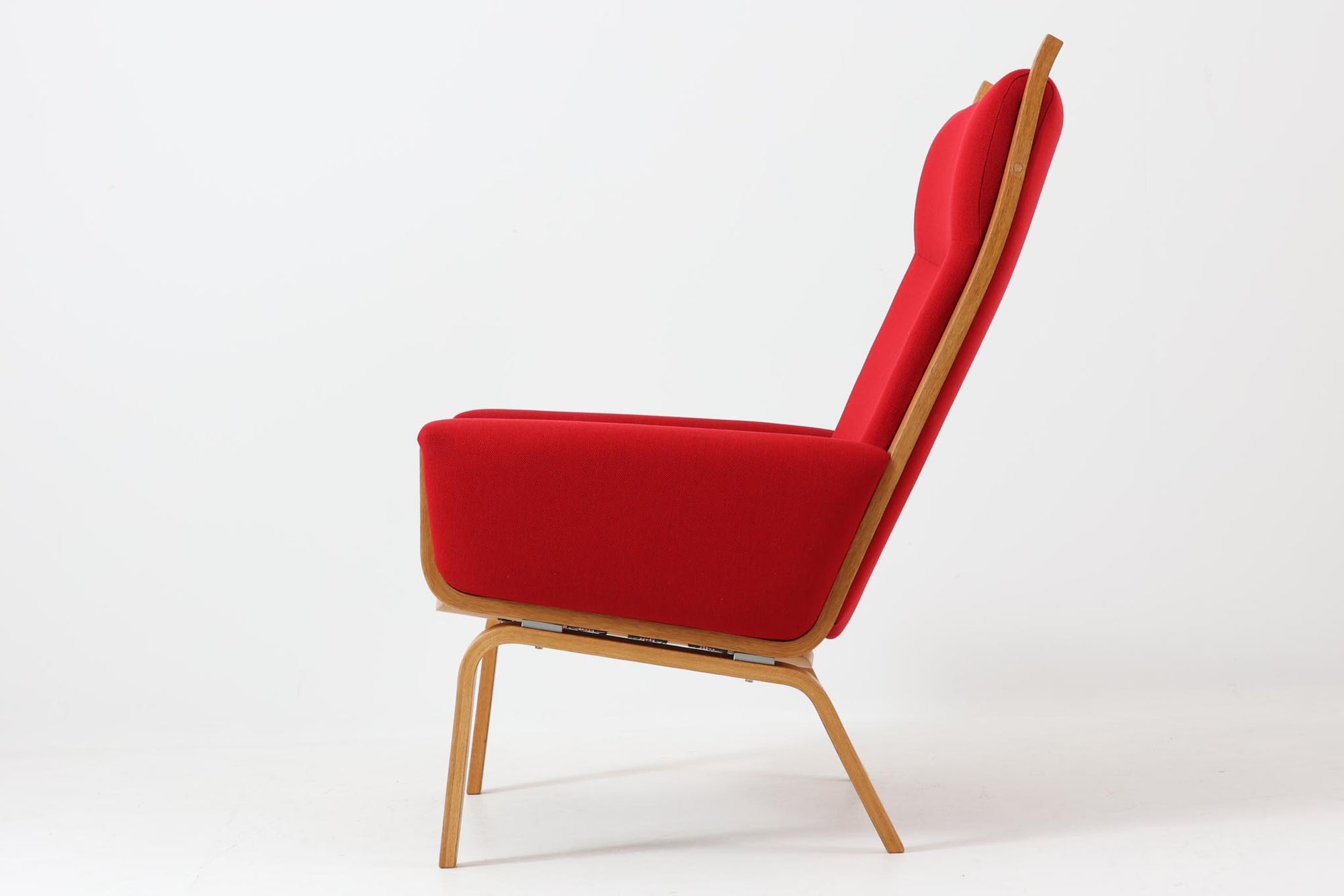 Hans J. Wegner（ハンス・J・ウェグナー）が1960年代にデザインし、Getama（ゲタマ）社によって製造されたGE501Aモデルのハイバックシングルソファ。当時としては珍しく、フレームにプライウッドが使用されています。フレームには堅牢で美しい木目を持つオーク材を使用し、直線と曲線が融合した造形が北欧家具らしい洗練された印象を与えます。張地には鮮やかな赤のファブリックを使用し、空間にアクセントを添えると同時に、快適性と耐久性も兼ね備えた仕上がりです。ヴィンテージならではの存在感と高い実用性を兼ね備えた一脚として、リビングや読書スペースに最適です。