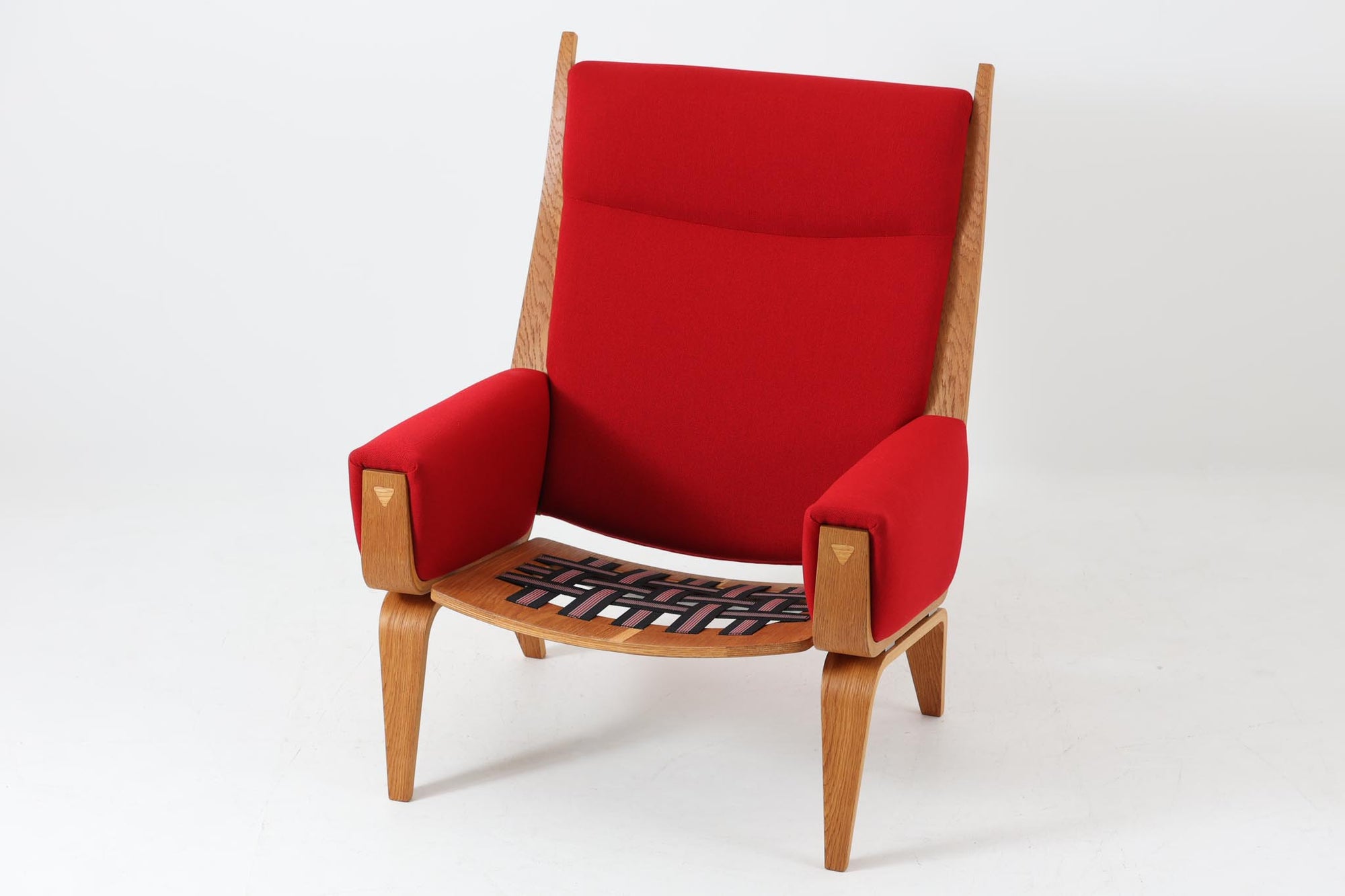 Hans J. Wegner（ハンス・J・ウェグナー）が1960年代にデザインし、Getama（ゲタマ）社によって製造されたGE501Aモデルのハイバックシングルソファ。当時としては珍しく、フレームにプライウッドが使用されています。フレームには堅牢で美しい木目を持つオーク材を使用し、直線と曲線が融合した造形が北欧家具らしい洗練された印象を与えます。張地には鮮やかな赤のファブリックを使用し、空間にアクセントを添えると同時に、快適性と耐久性も兼ね備えた仕上がりです。ヴィンテージならではの存在感と高い実用性を兼ね備えた一脚として、リビングや読書スペースに最適です。