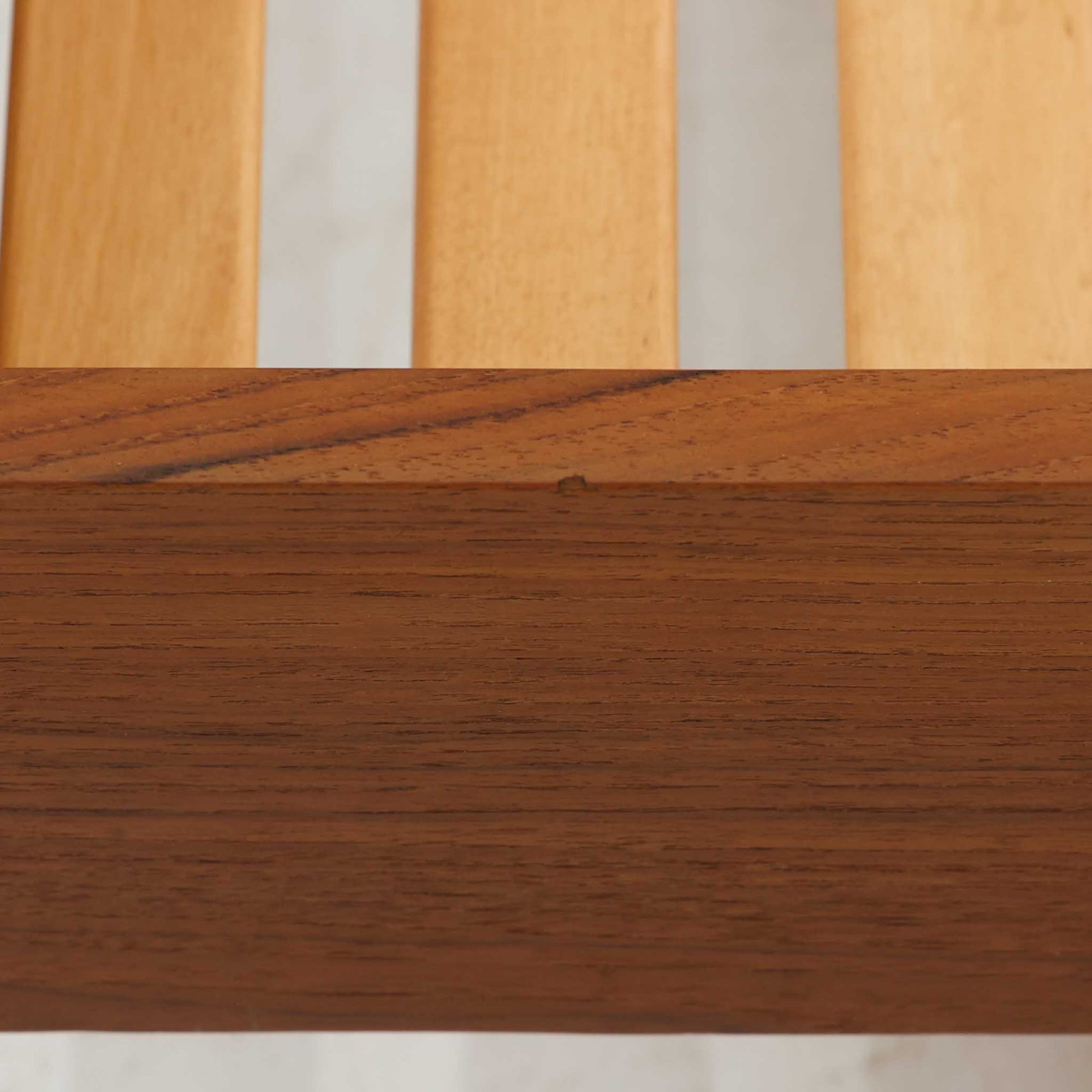 温かみのあるチーク材の木肌を生かした、北欧ビンテージのシングルベッドフレームです。直線を基調とした低めのフレームに丸脚を組み合わせ、すのこ状の床板によって通気性にも配慮された実用的な構造。側面には黒い天板の引出し式トレーを備え、眼鏡や本、飲み物などを置く簡易テーブルとして便利に使えます。経年によって深みを増した色合いと無駄のない端正な造形が、寝室に落ち着きとビンテージならではの存在感を添える一台です。
